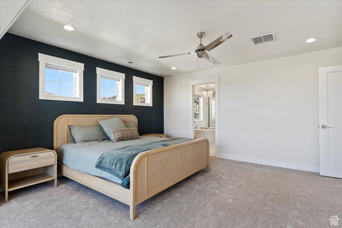 Carpeted bedroom with ceiling fan and ensuite bath