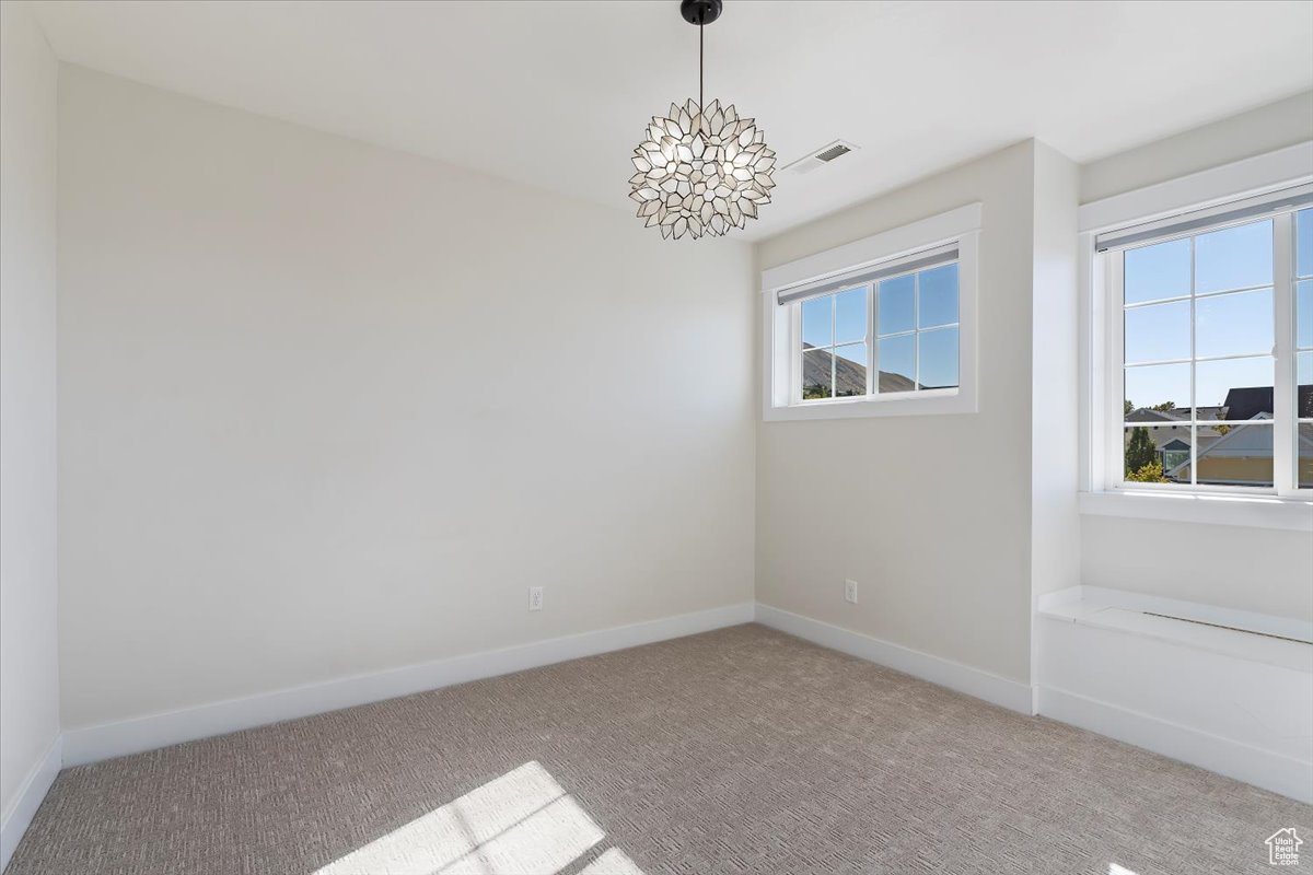 Unfurnished room with carpet and an inviting chandelier