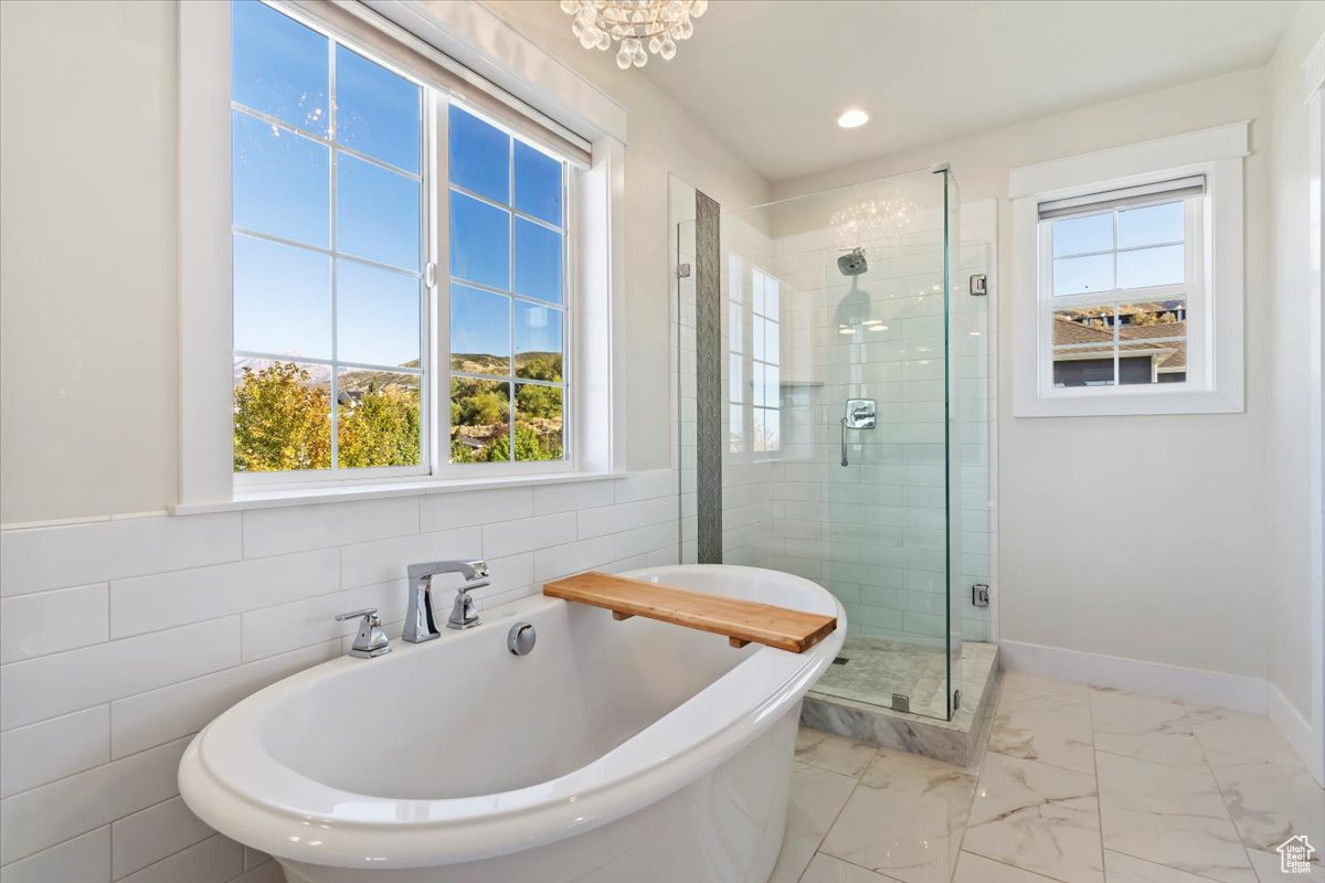 Bathroom featuring plus walk in shower, tile walls, and a wealth of natural light