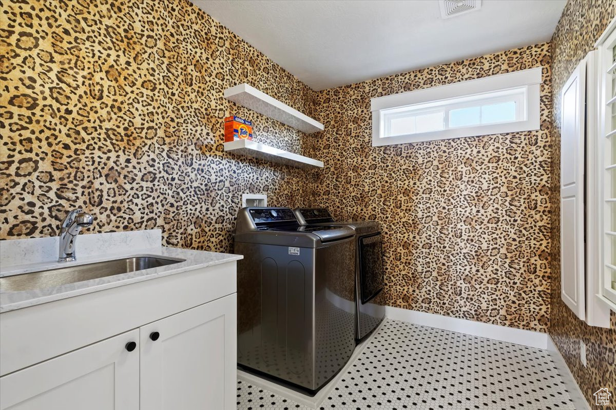 Laundry room featuring washer and clothes dryer, cabinets, and sink