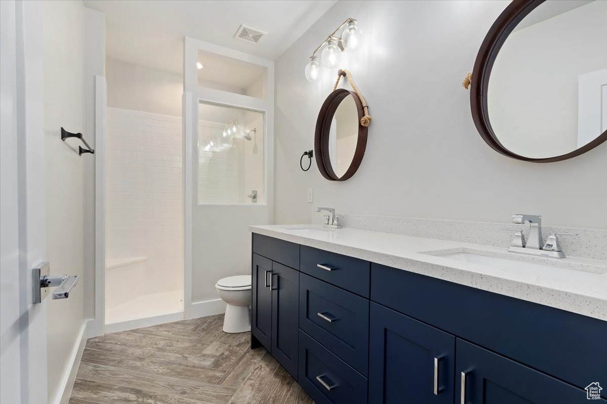 Bathroom with walk in shower, hardwood / wood-style floors, vanity, and toilet