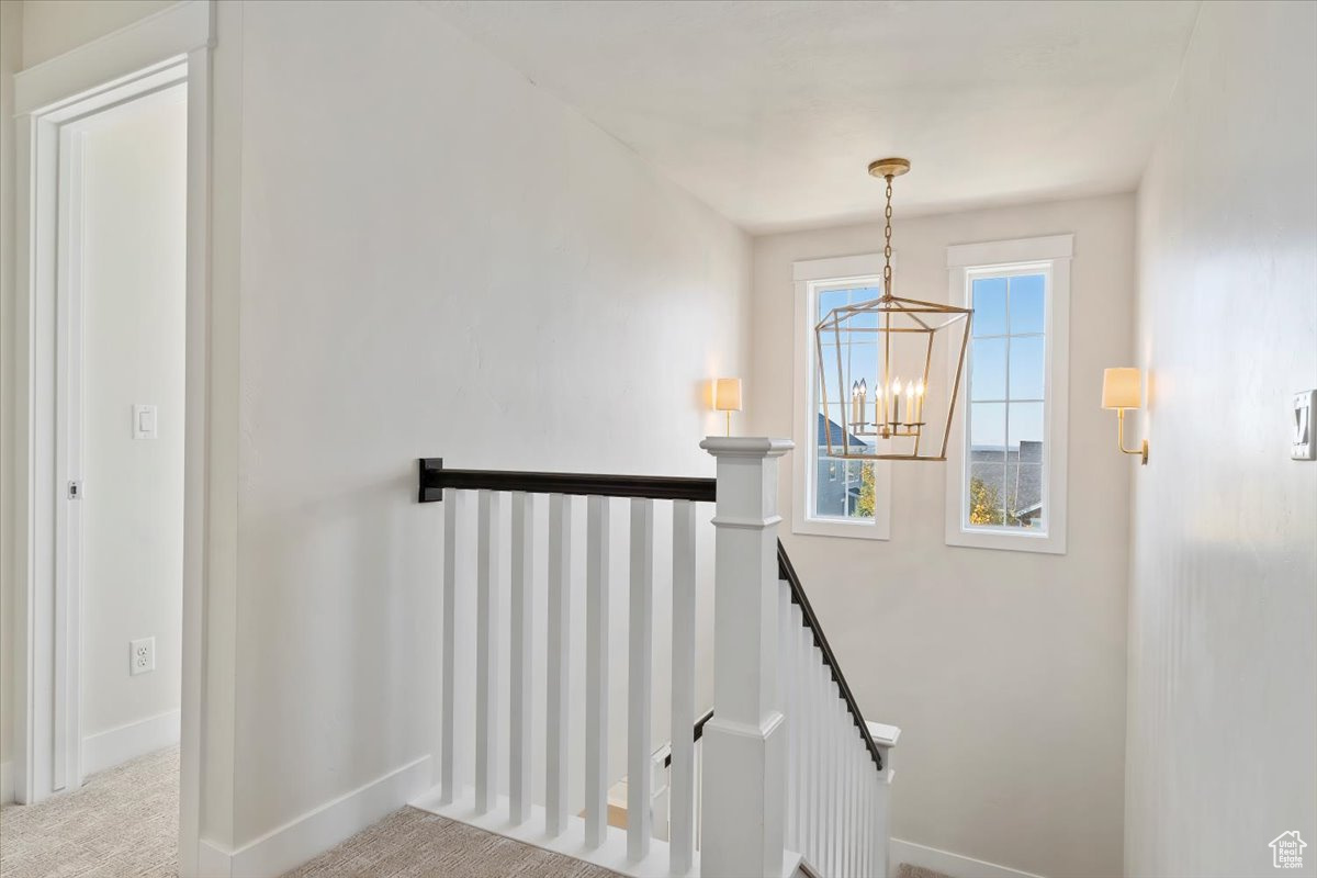 Stairs featuring carpet floors and a chandelier