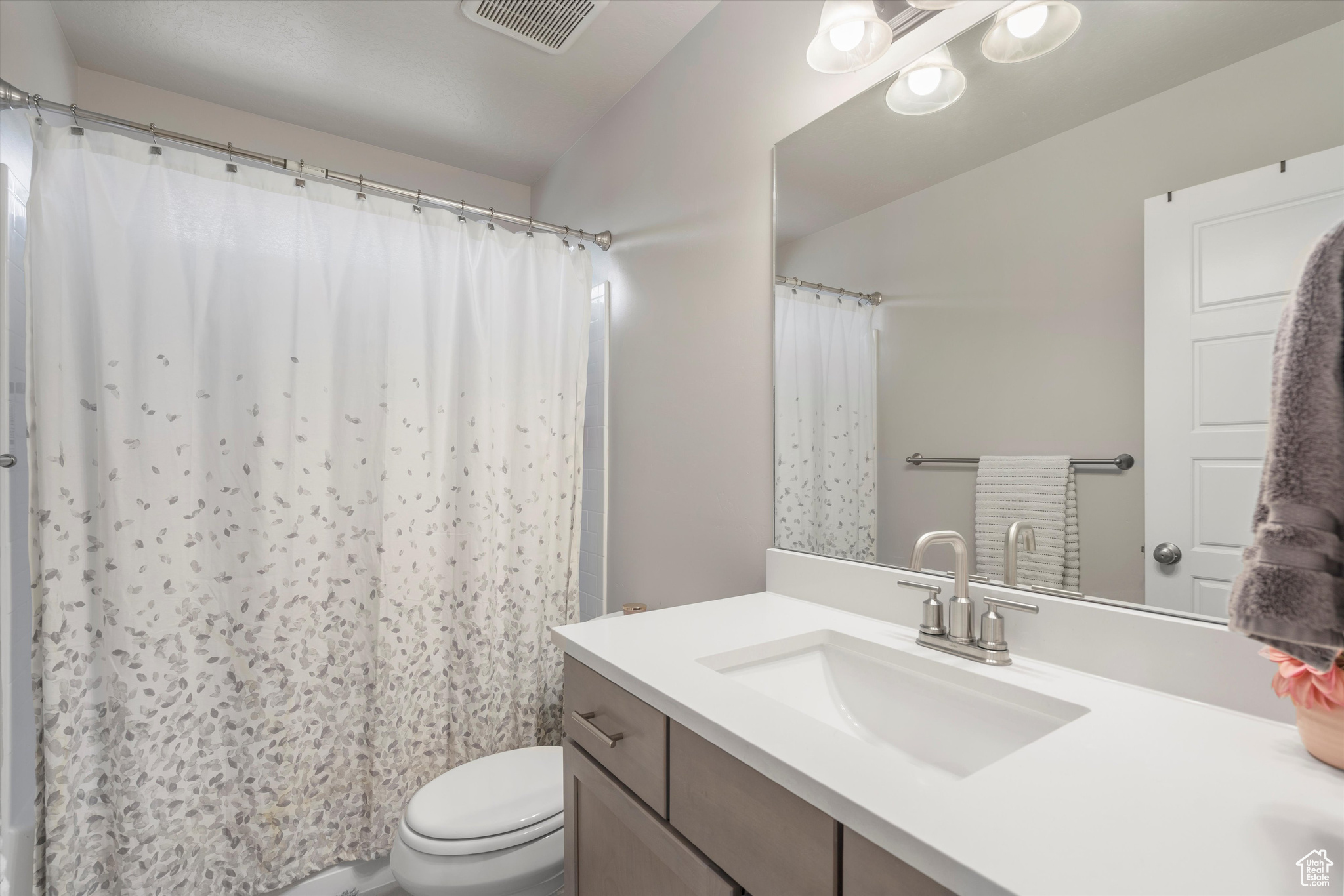 Full bathroom on main floor with vanity, lofted ceiling, toilet, and curtained shower