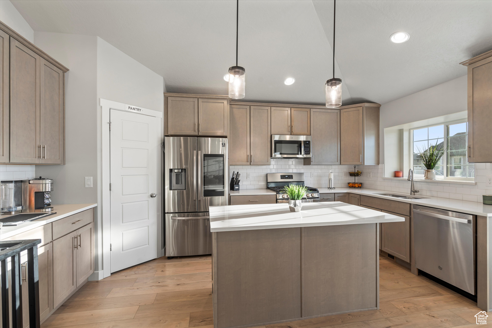 Kitchen with pendant lighting, stainless steel appliances, light wood-type flooring, and sink