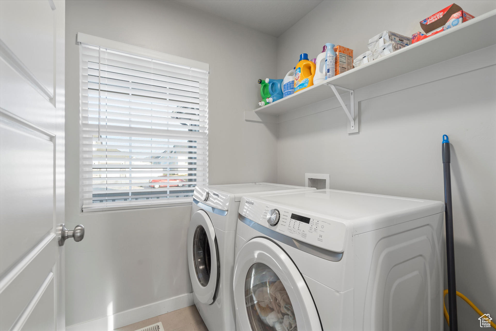 Washroom with washing machine and clothes dryer and light tile patterned floors