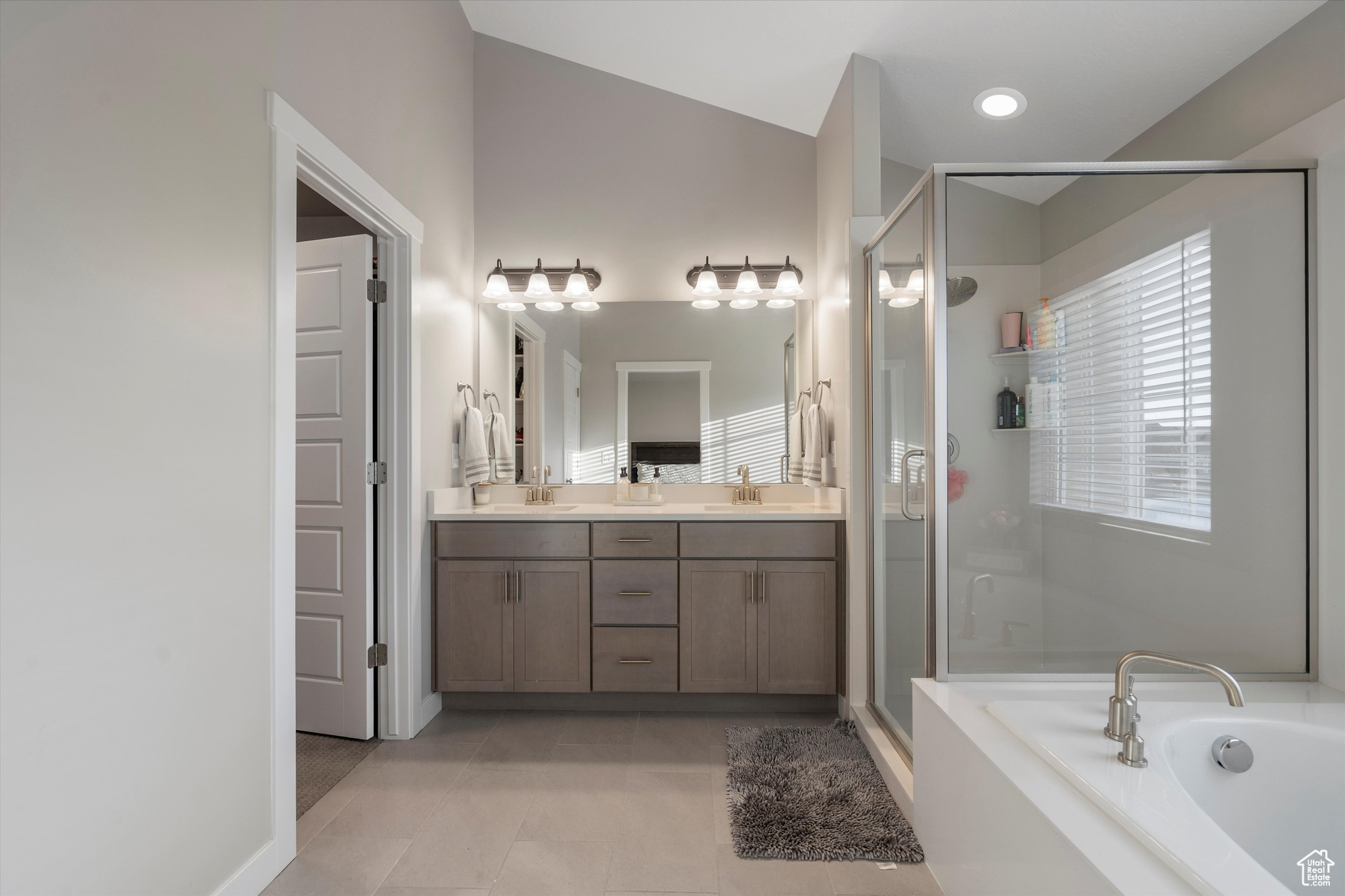 Master bathroom featuring lofted ceiling, vanity, separate shower and tub, and tile patterned flooring