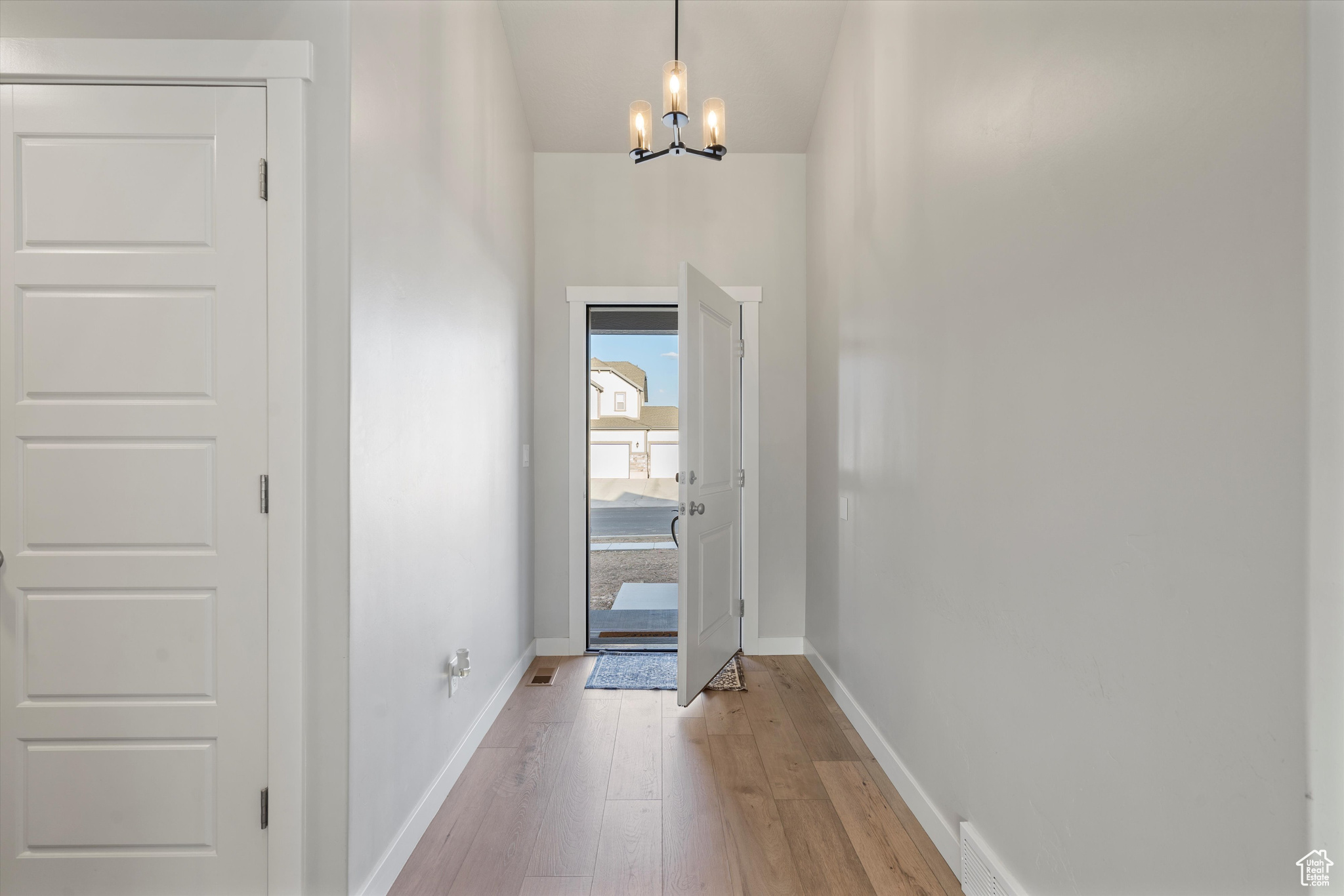 Doorway featuring an inviting chandelier and light LVP flooring