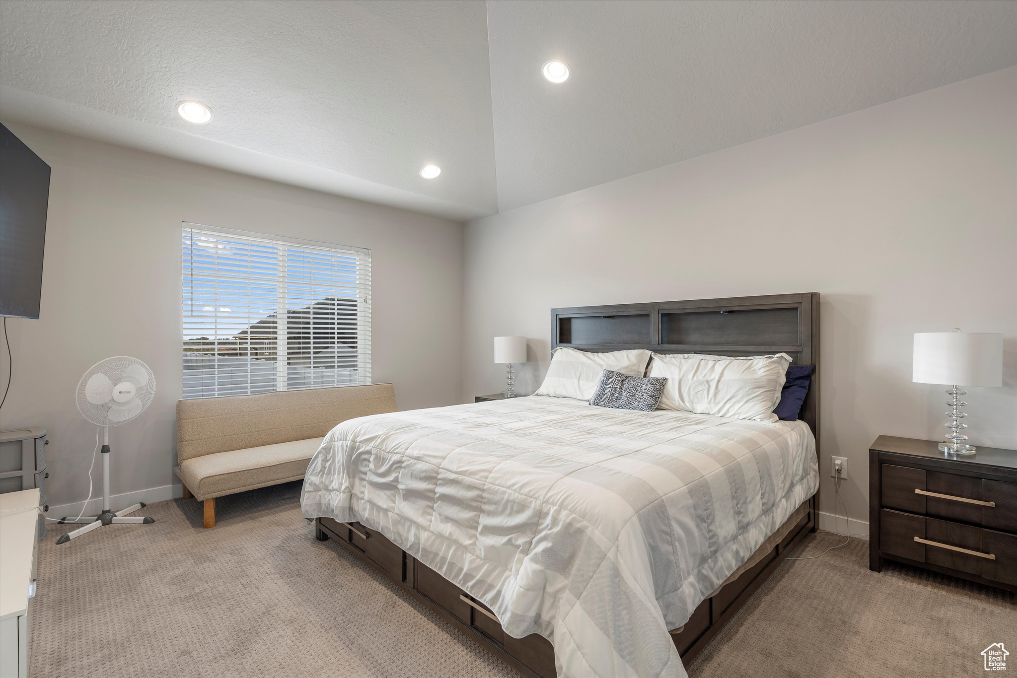 Master bedroom with light carpet and vaulted ceiling