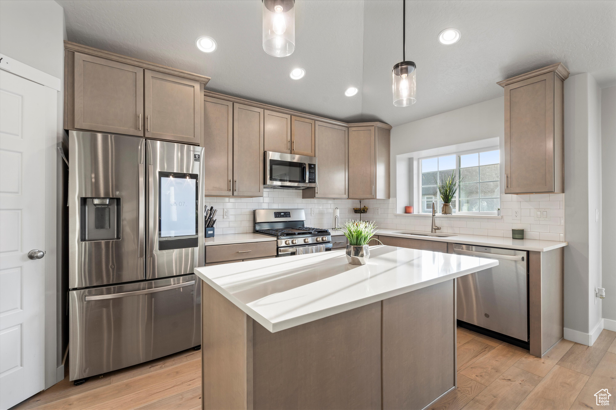 Kitchen with center island, sink, hanging light fixtures, and stainless steel appliances