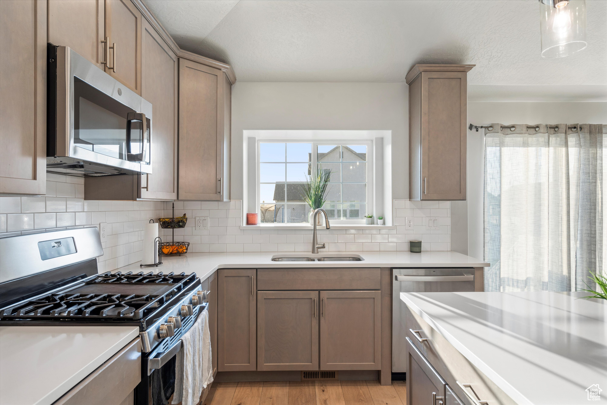 Kitchen with stainless steel appliances, sink, decorative backsplash.