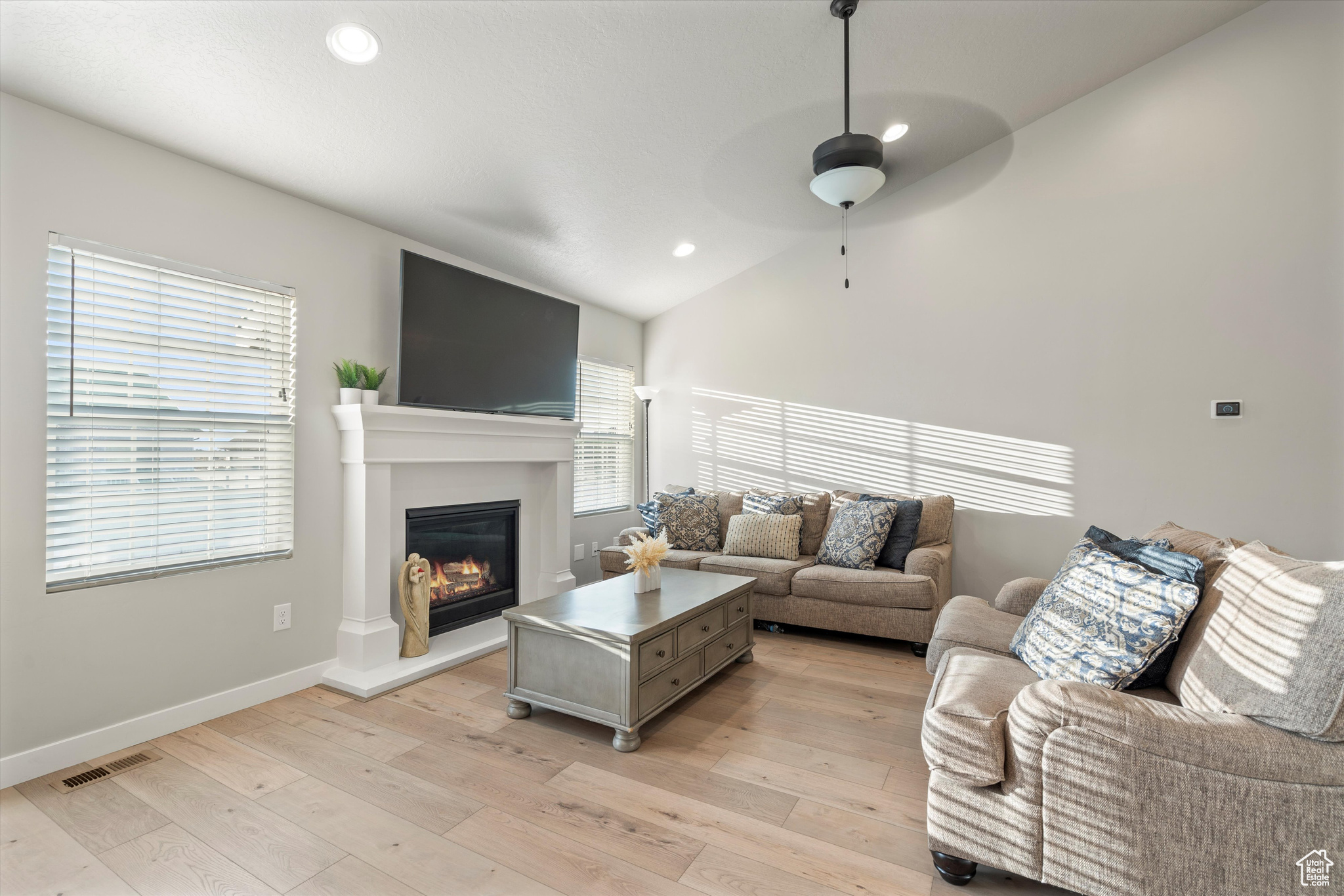 Living room with LVP flooring, vaulted ceiling, and a healthy amount of sunlight