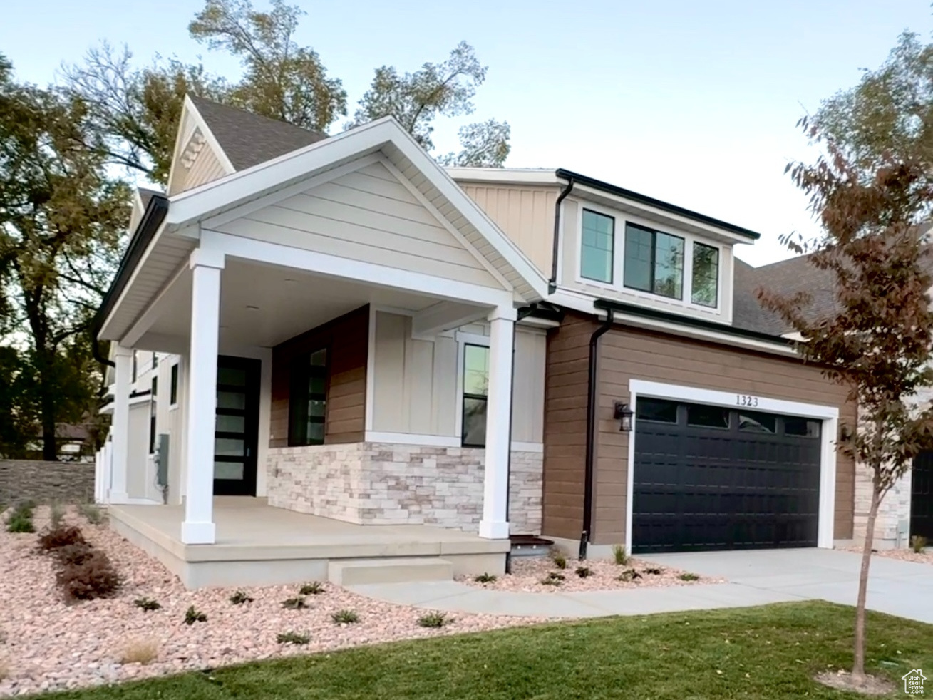 View of front facade with a garage, a porch, and a front lawn