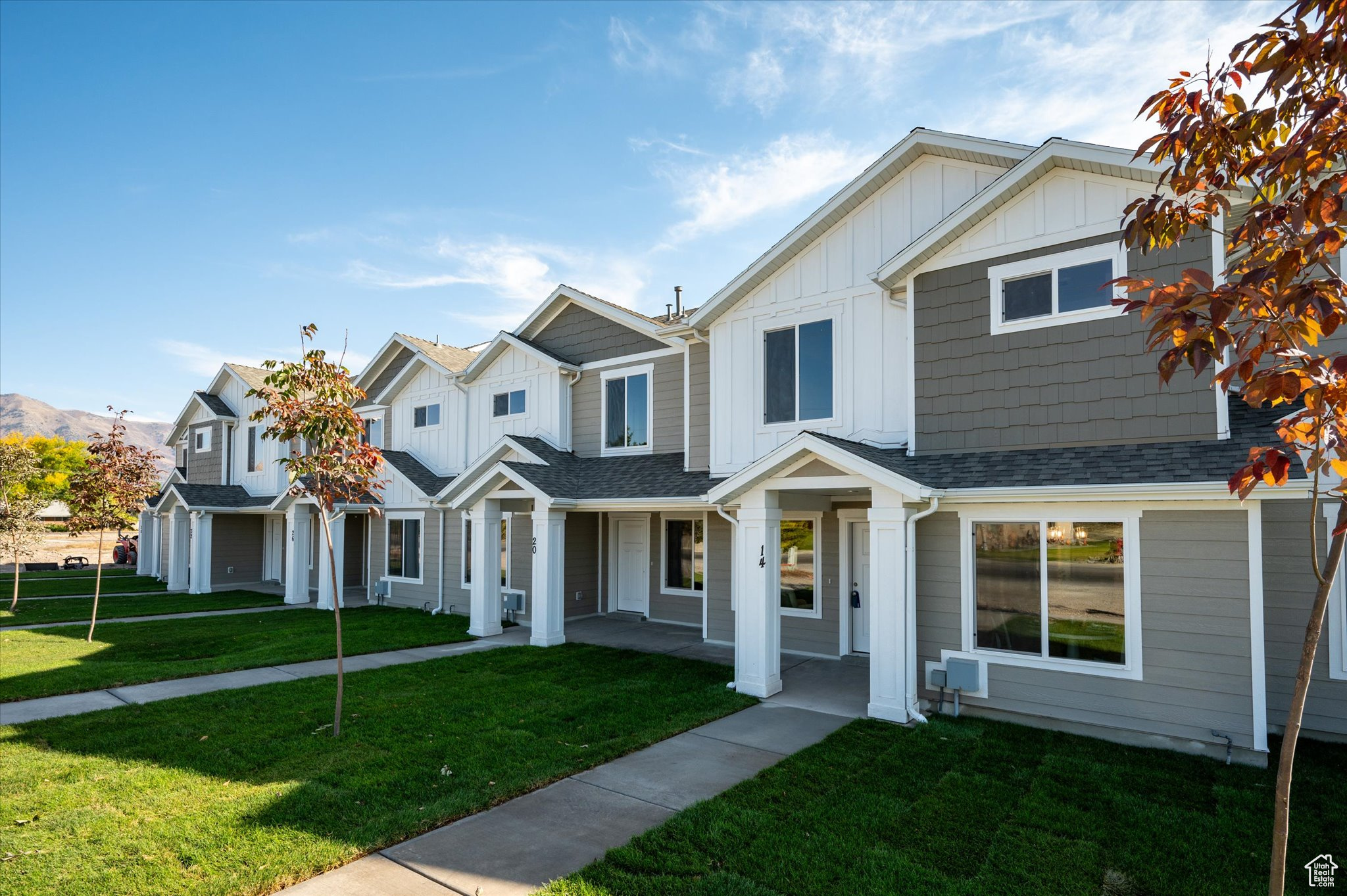 View of front of home with board and batten siding, a front lawn, and roof with shingles