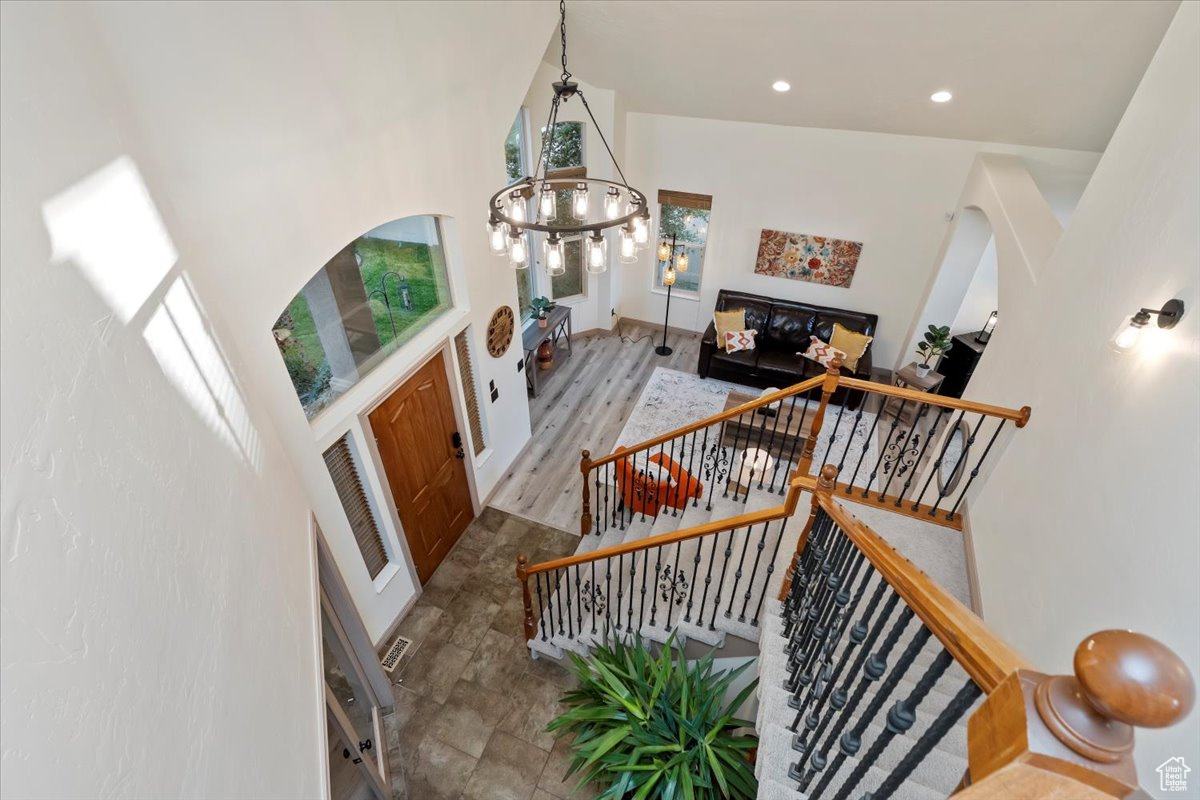 Stairway with hardwood / wood-style floors, a notable chandelier, and a towering ceiling