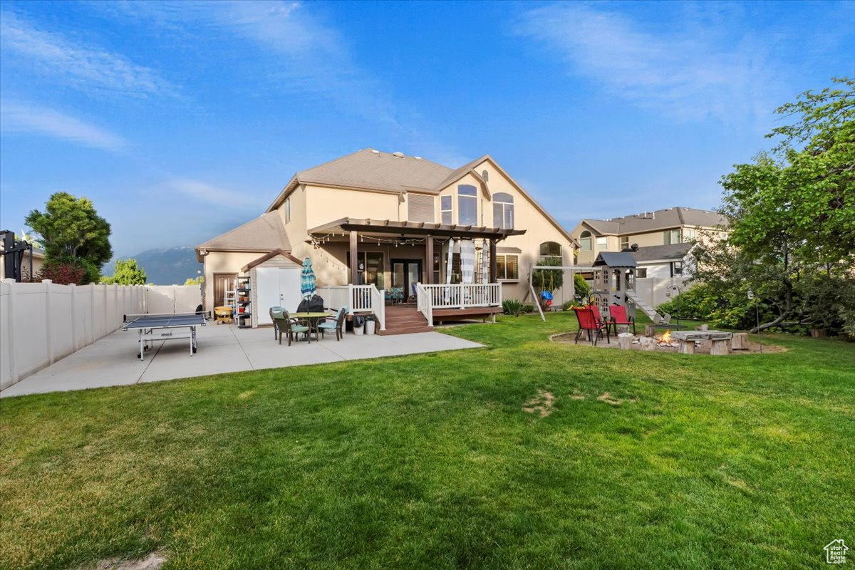 Back of property featuring a yard, a wooden deck, a pergola, and a patio area