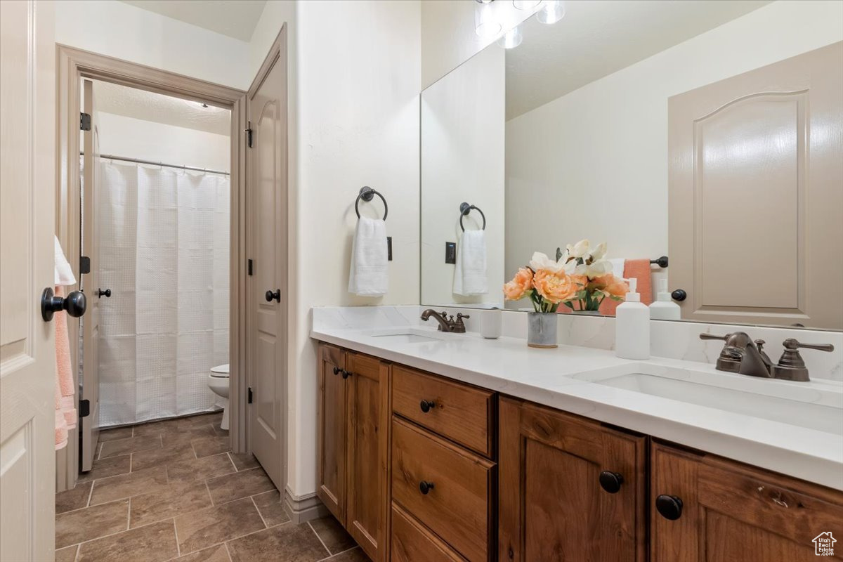 Bathroom featuring a shower with curtain, vanity, and toilet; new quartz countertops