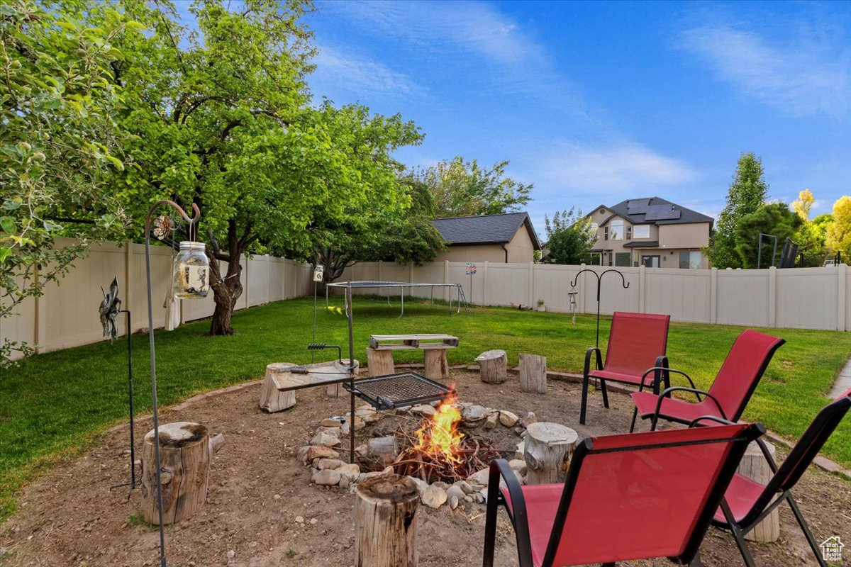 View of yard with a trampoline and a fire pit