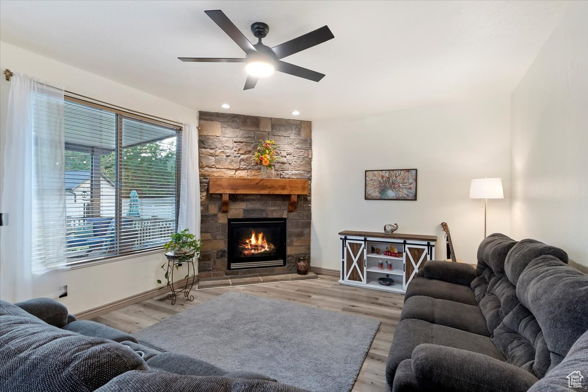 Living room featuring a fireplace, ceiling fan, and light hardwood / wood-style flooring