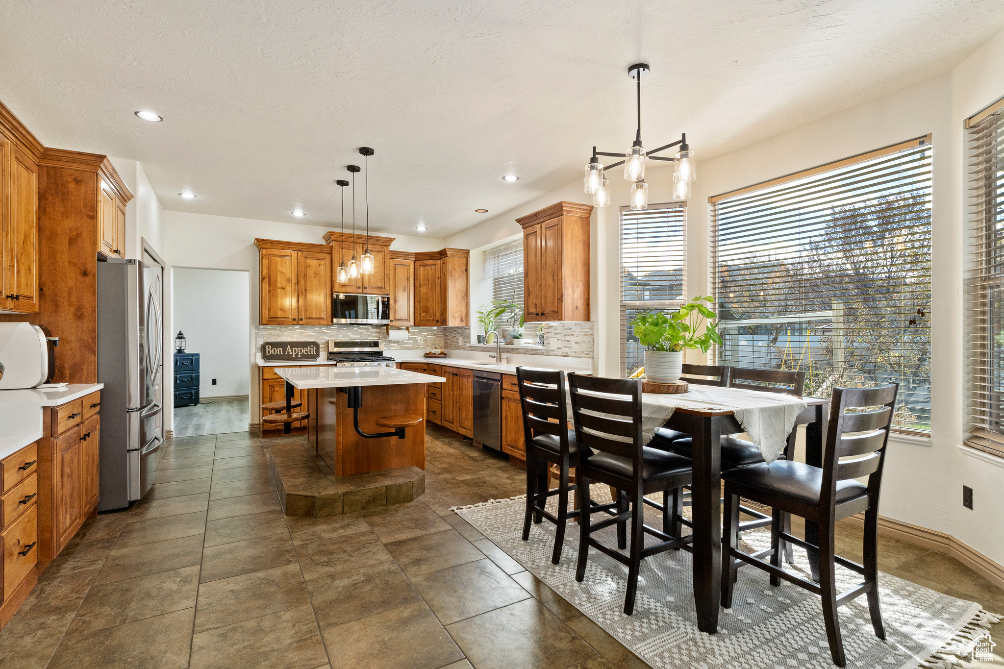 Kitchen featuring a center island, a kitchen breakfast bar, decorative light fixtures, decorative backsplash, and appliances with stainless steel finishes