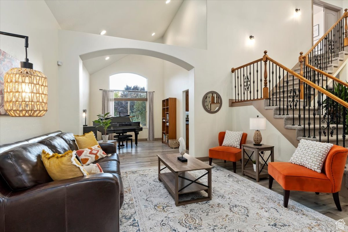 Living room featuring light hardwood / wood-style floors, high vaulted ceiling, and a notable chandelier