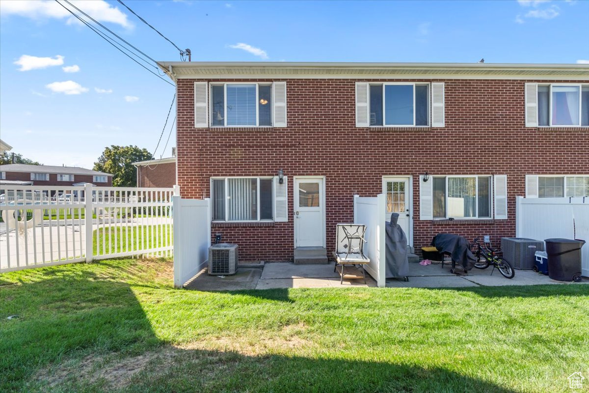 Back of house featuring a yard, central air condition unit, and a patio area