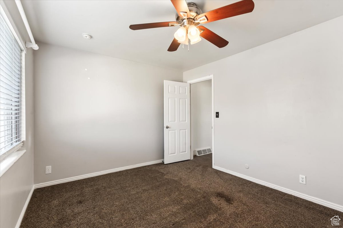 Spare room featuring ceiling fan and dark colored carpet