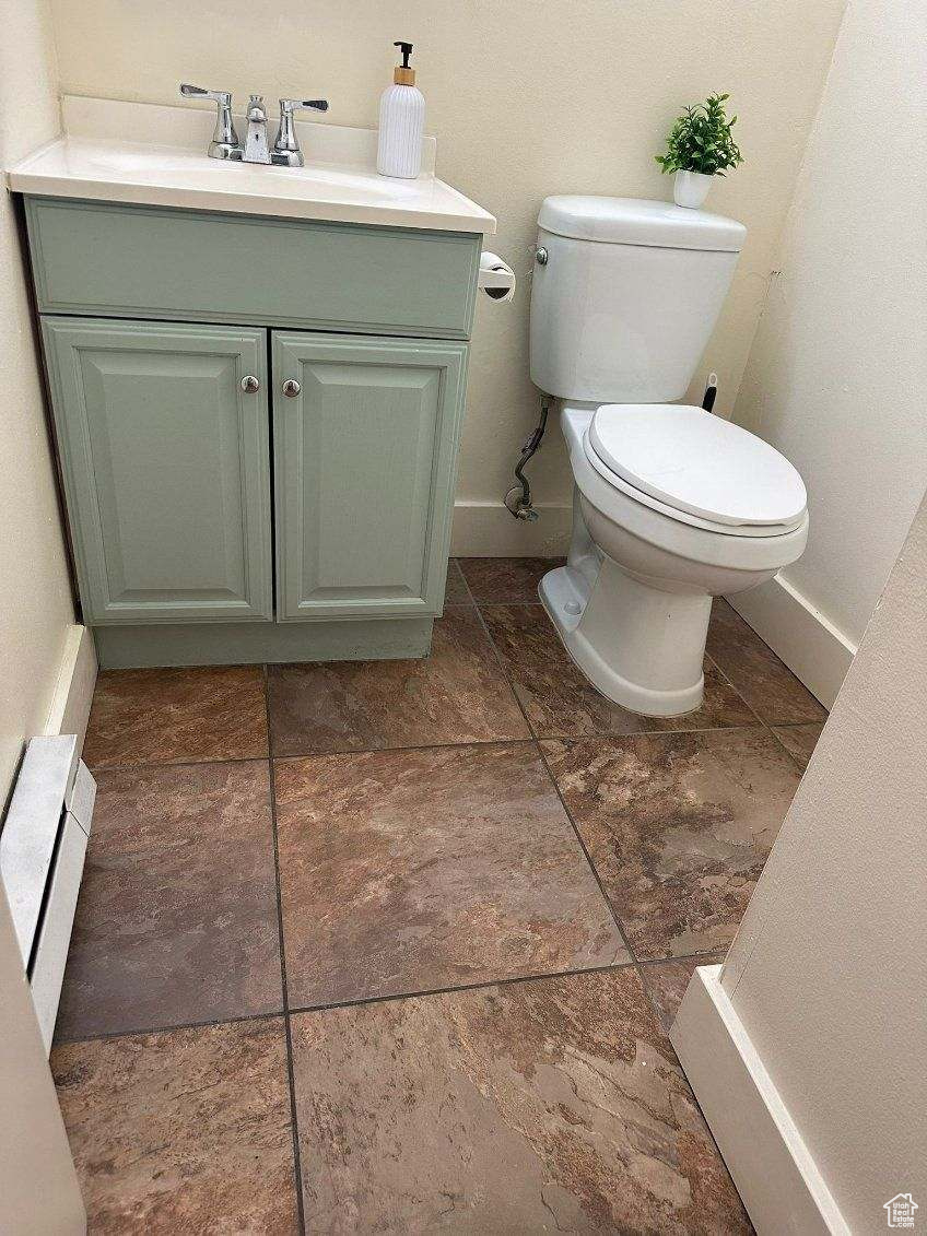 Bathroom featuring vanity, toilet, and baseboard heating