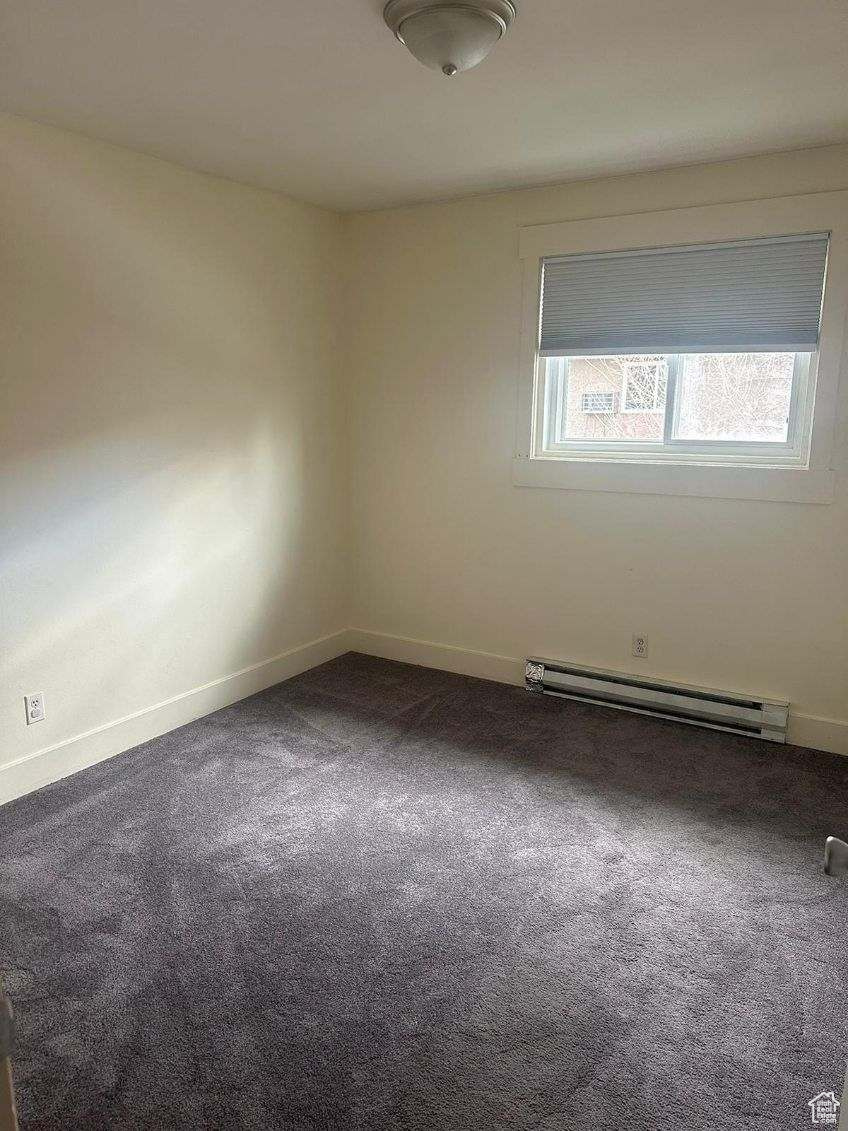 Carpeted spare room with baseboard heating