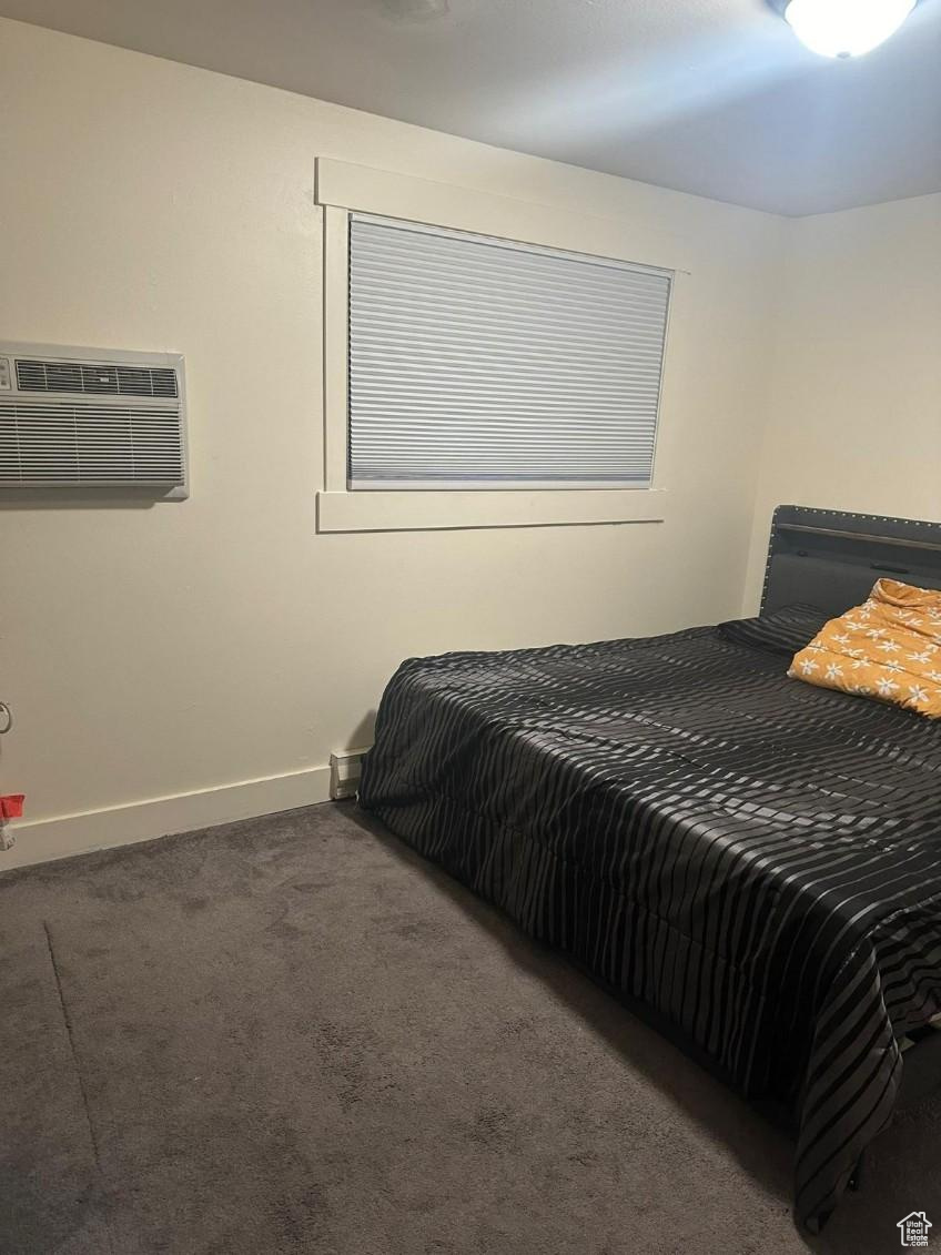 Bedroom featuring a wall mounted air conditioner and dark carpet