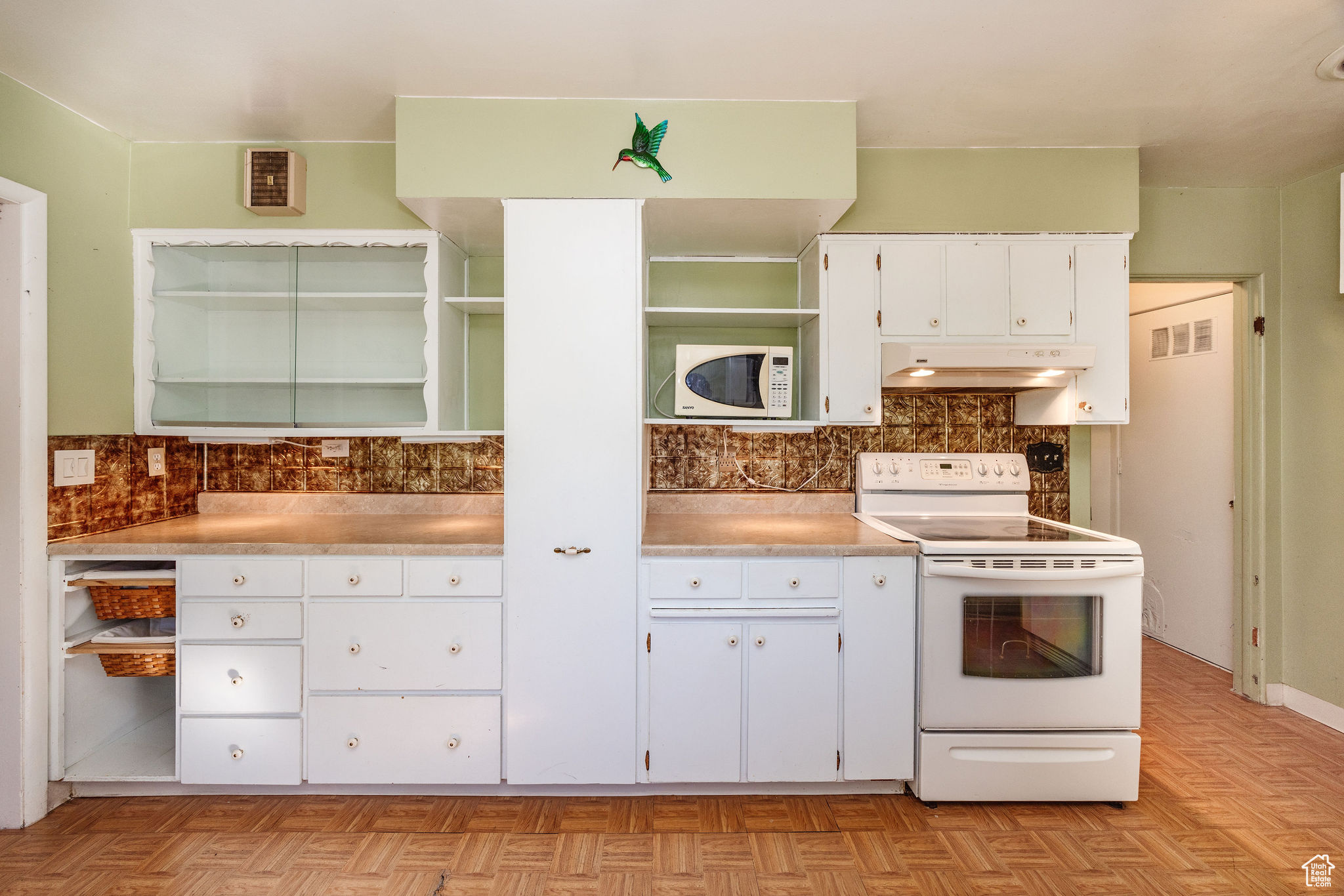 Kitchen with white cabinets, tasteful backsplash, white appliances, and light parquet style floors