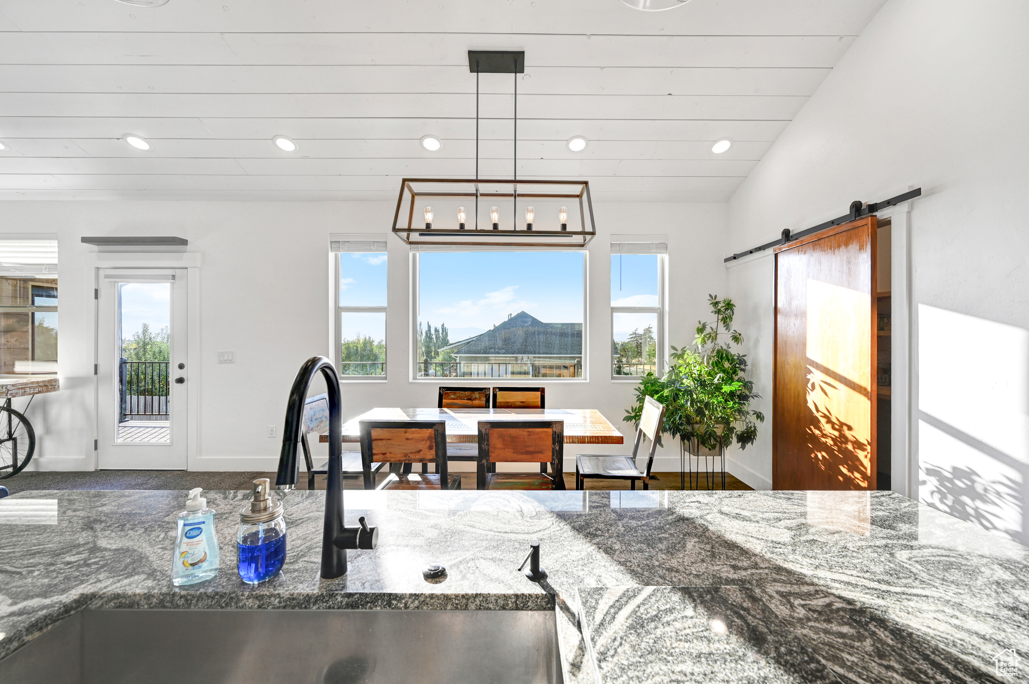 Kitchen featuring lofted ceiling, wood-type flooring, dark stone countertops, sink, and a barn door