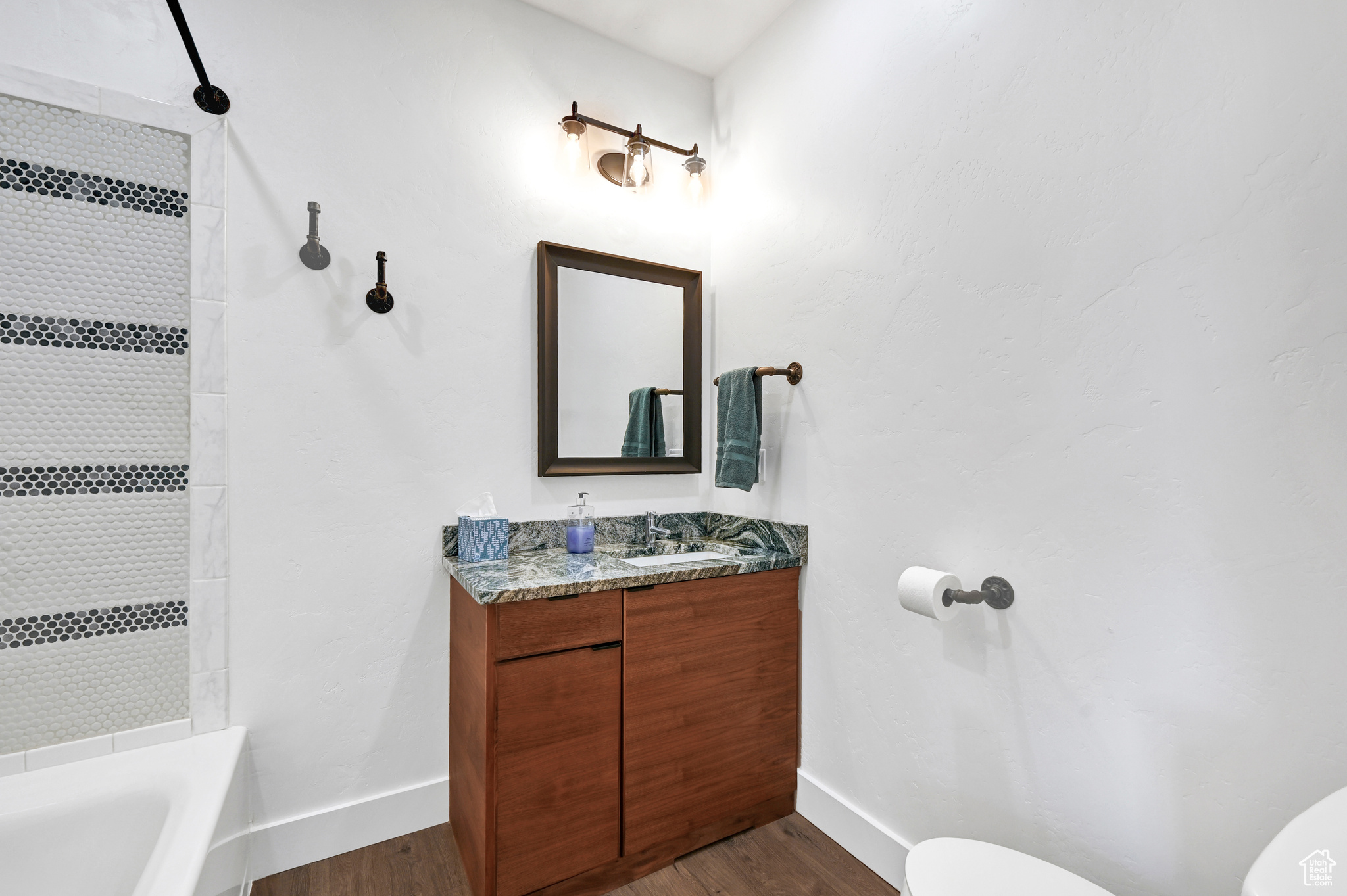 Full bathroom with tiled shower / bath, hardwood / wood-style flooring, vanity, and toilet