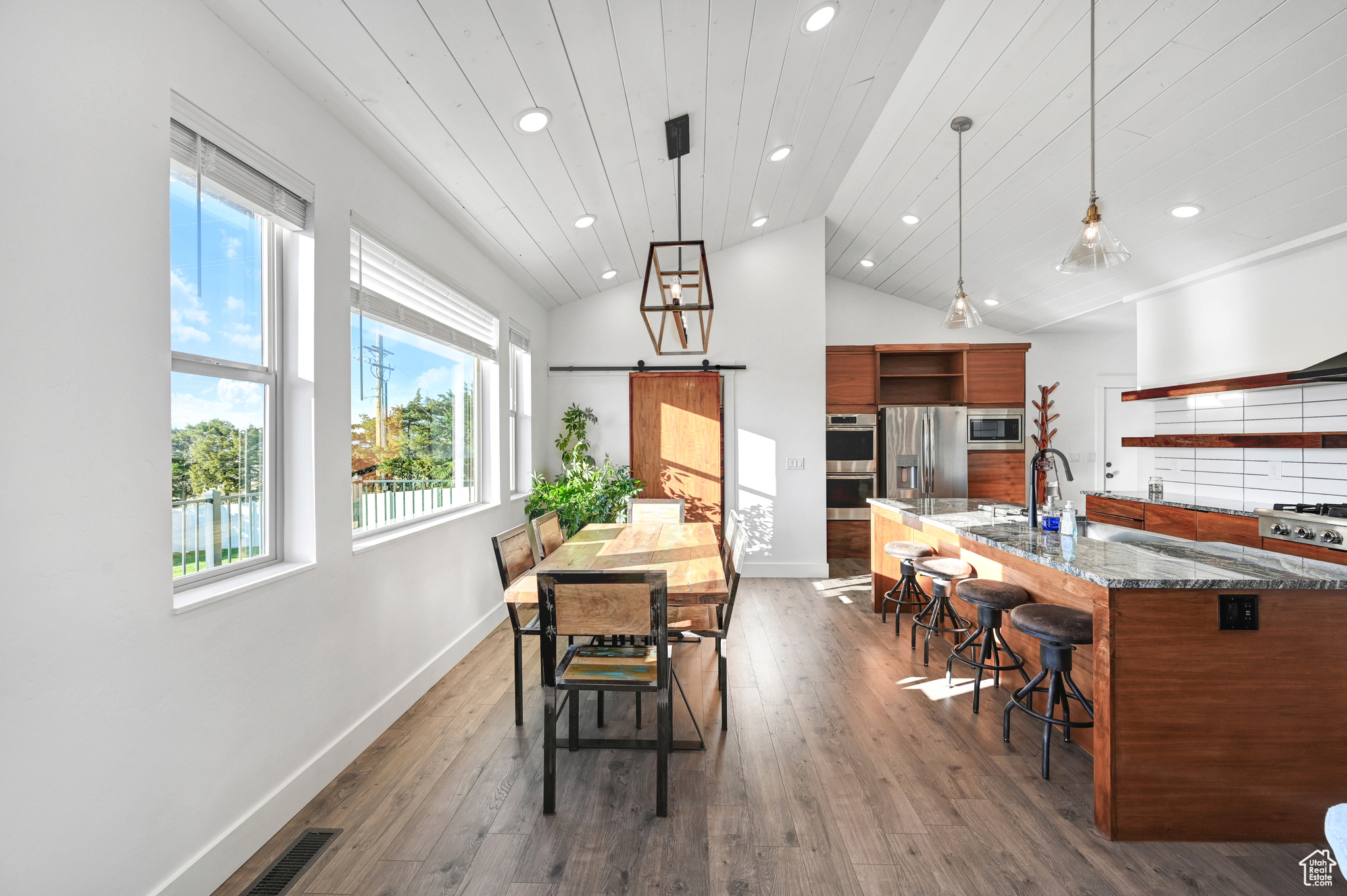 Dining space featuring wood ceiling, sink, high vaulted ceiling, dark hardwood / wood-style floors, and a barn door