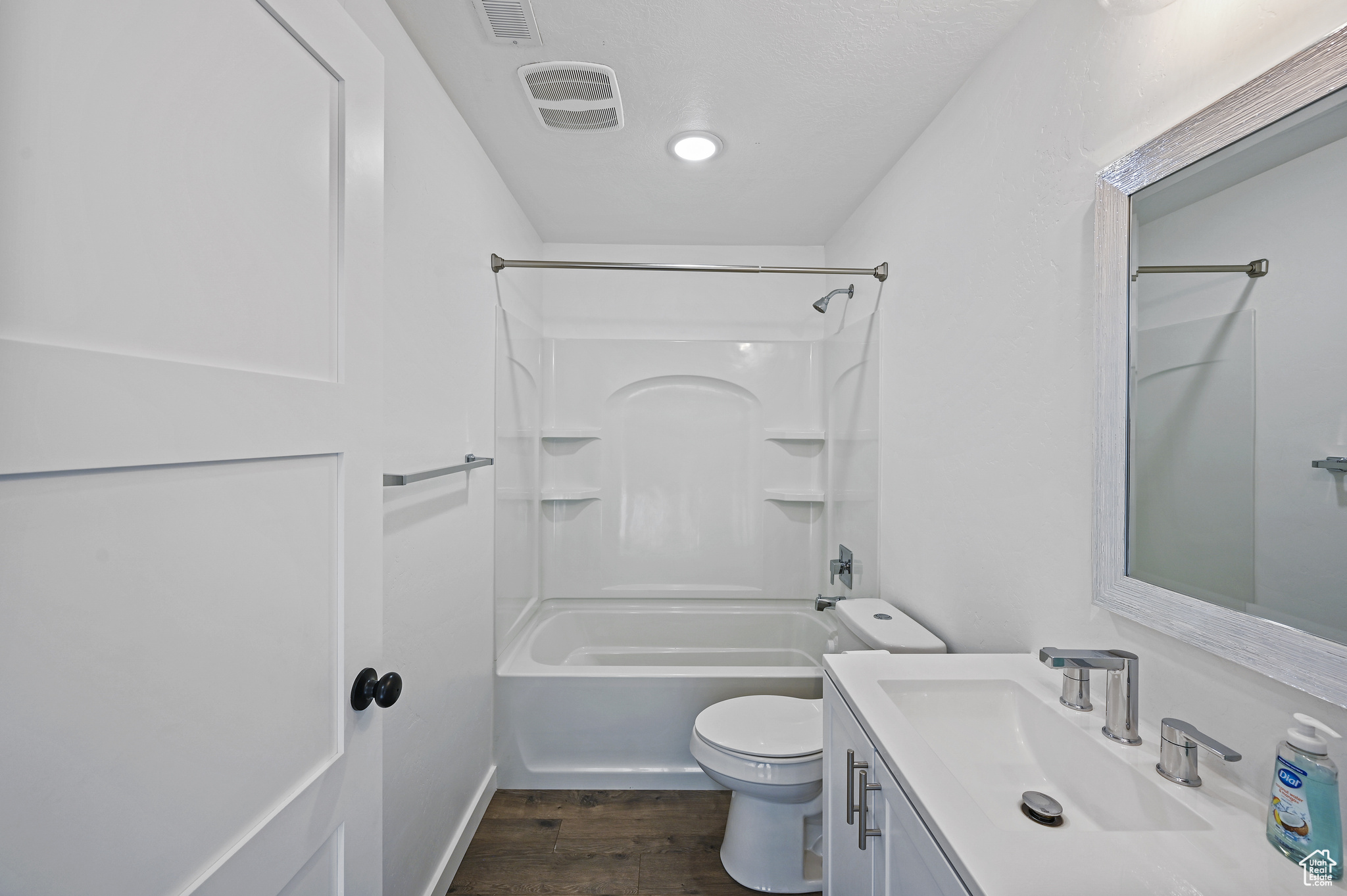 Full bathroom with wood-type flooring, bathtub / shower combination, vanity, and toilet