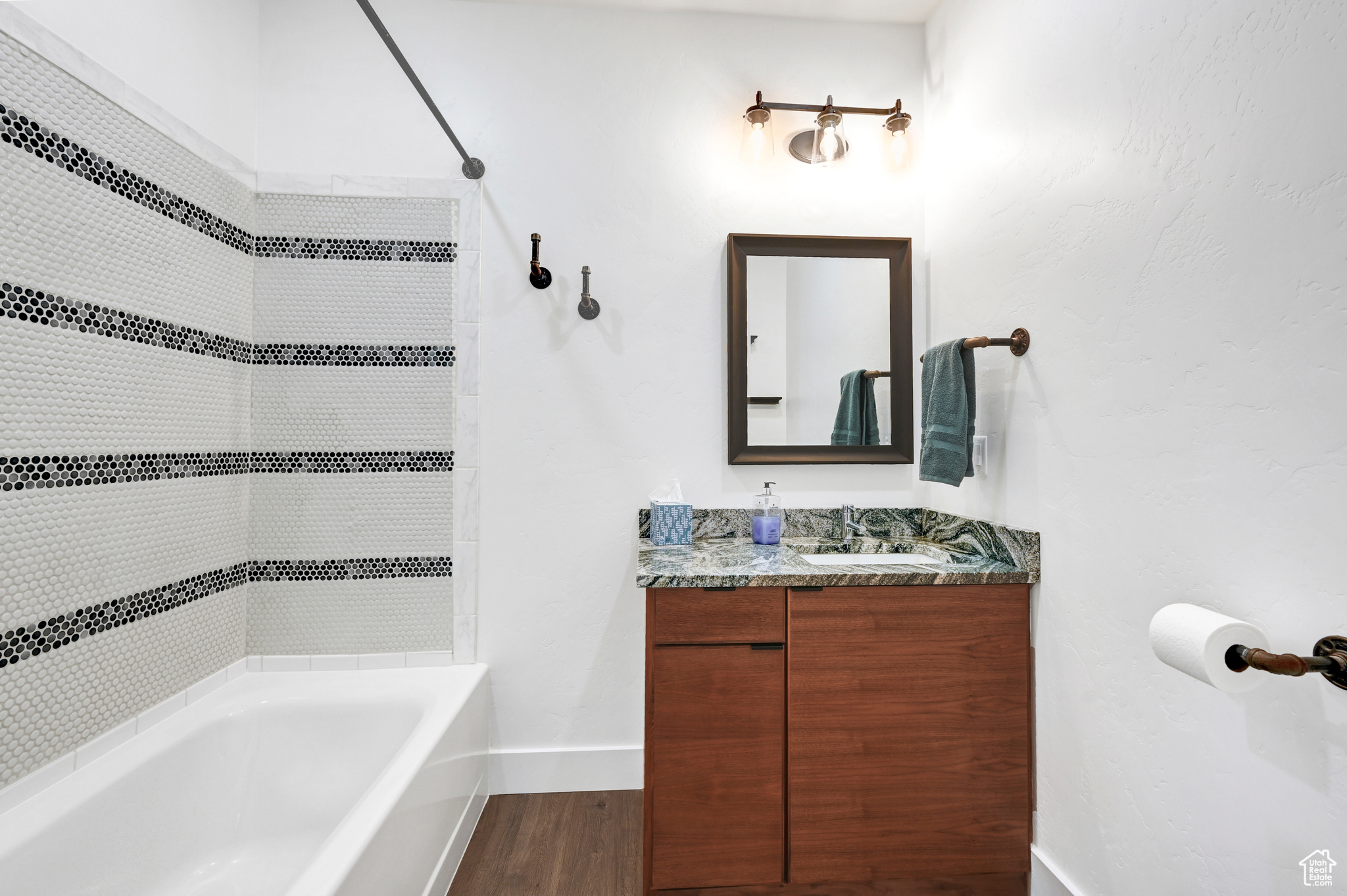 Bathroom with wood-type flooring, tiled shower / bath combo, and vanity