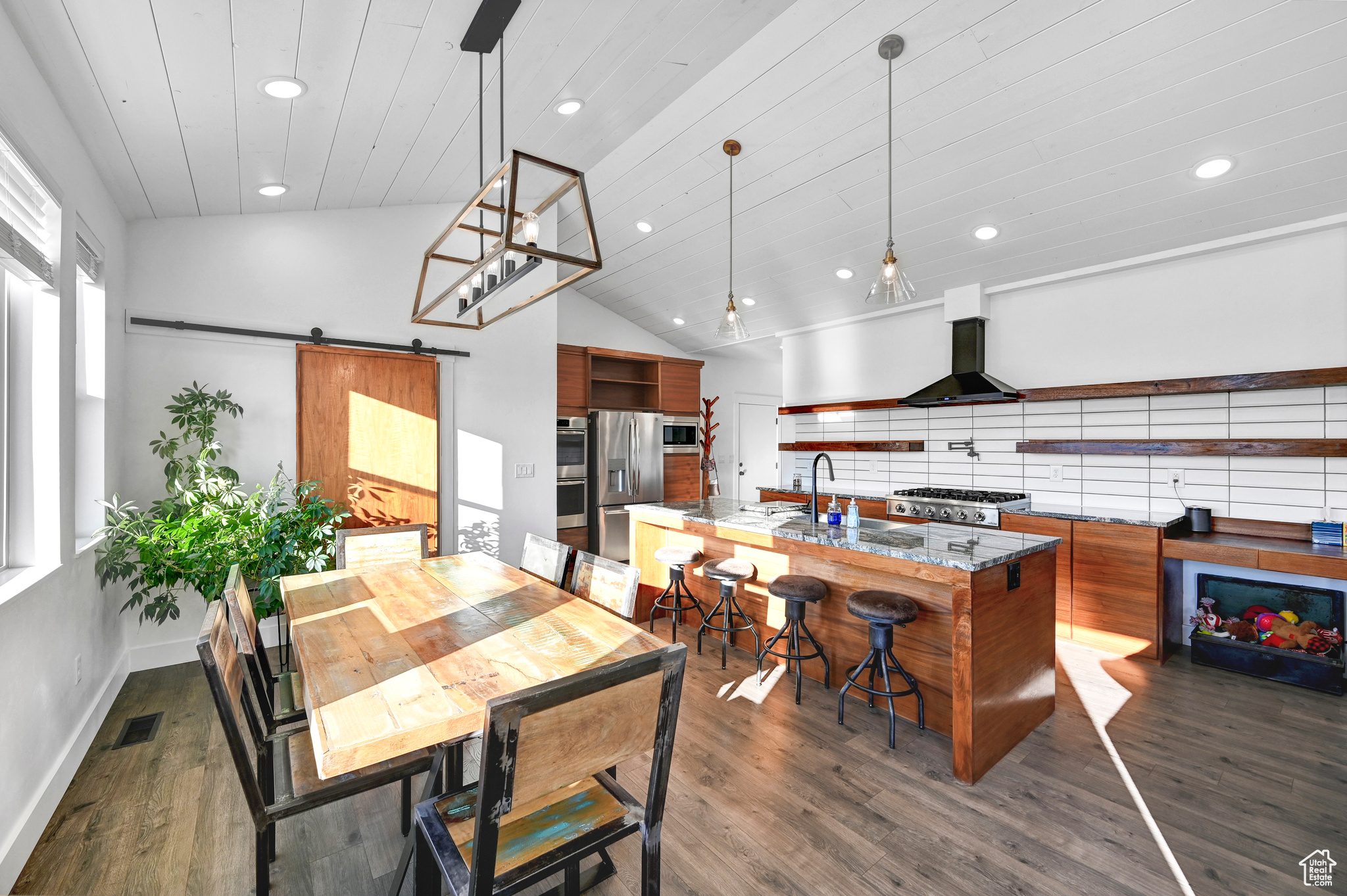 Dining space featuring a barn door, dark wood-type flooring, high vaulted ceiling, and sink