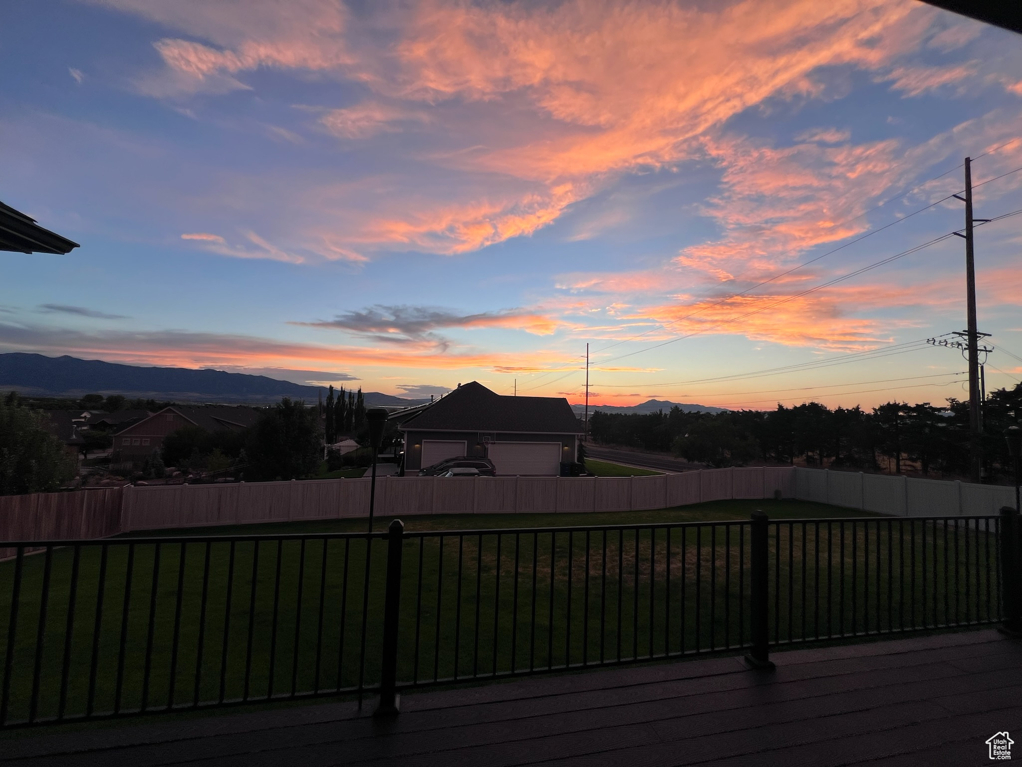 Deck at dusk featuring a mountain view and a lawn