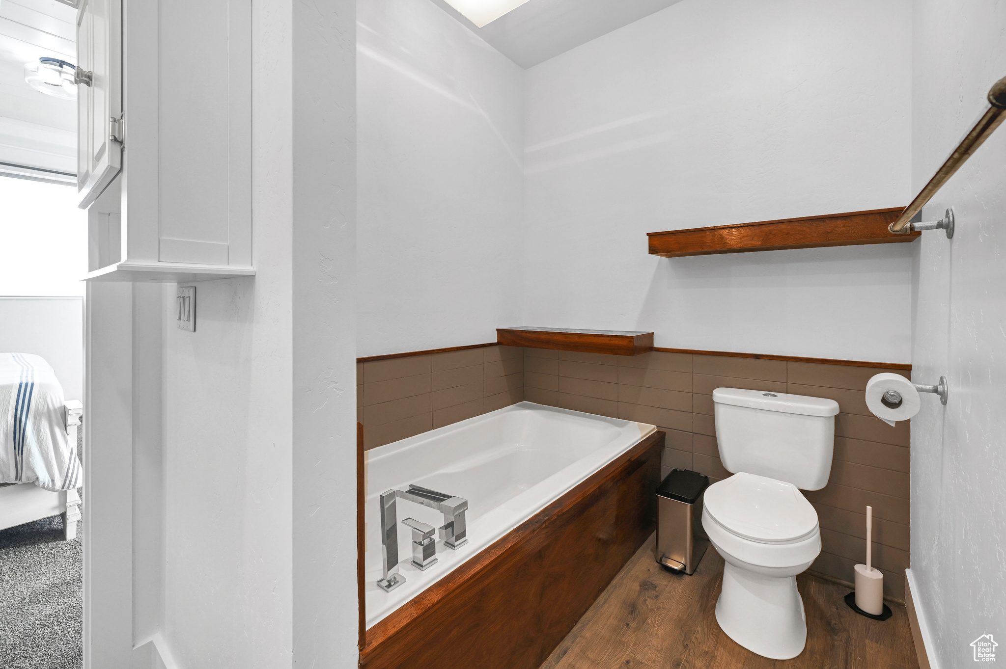 Bathroom with tile walls, toilet, and wood-type flooring