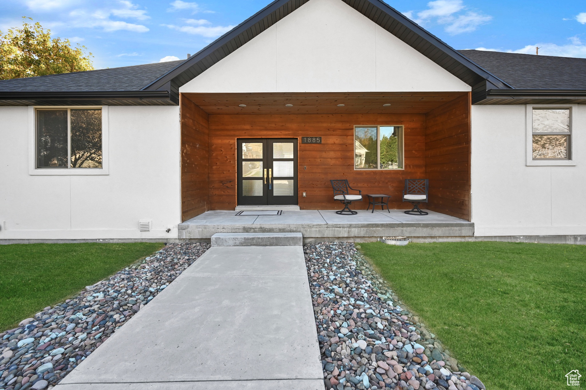 View of exterior entry featuring french doors and a lawn