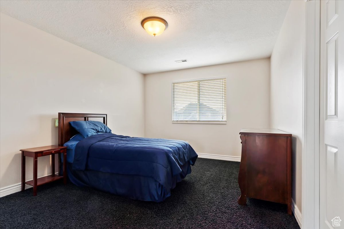 Bedroom featuring dark colored carpet and a textured ceiling