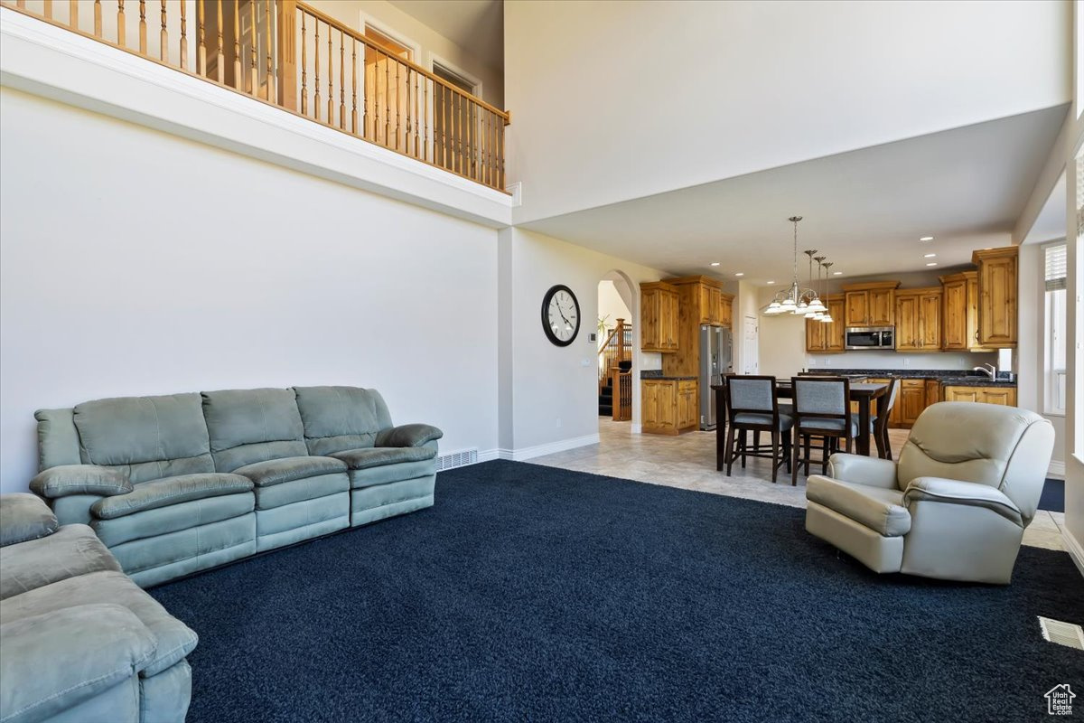 Living room with light carpet, a towering ceiling, and sink