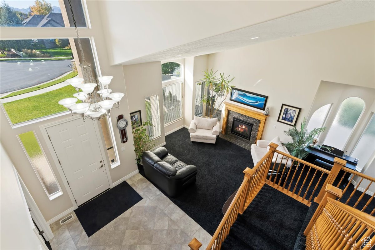 Foyer featuring a premium fireplace, a towering ceiling, and an inviting chandelier