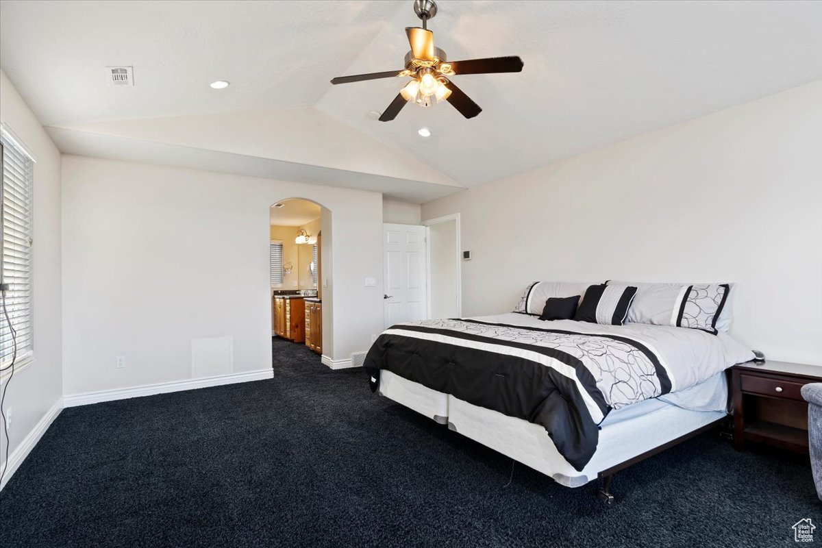 Bedroom with ceiling fan, dark carpet, vaulted ceiling, and multiple windows