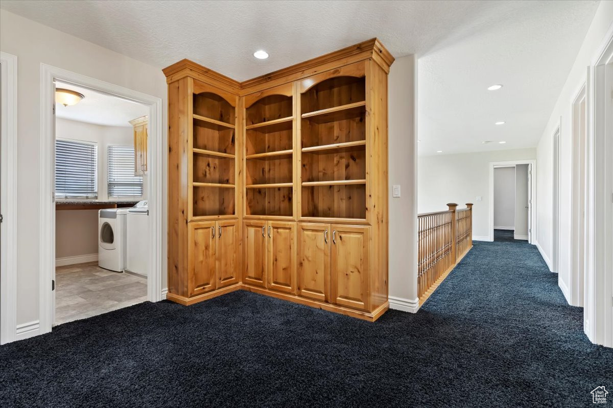 Hall featuring washing machine and clothes dryer and dark carpet