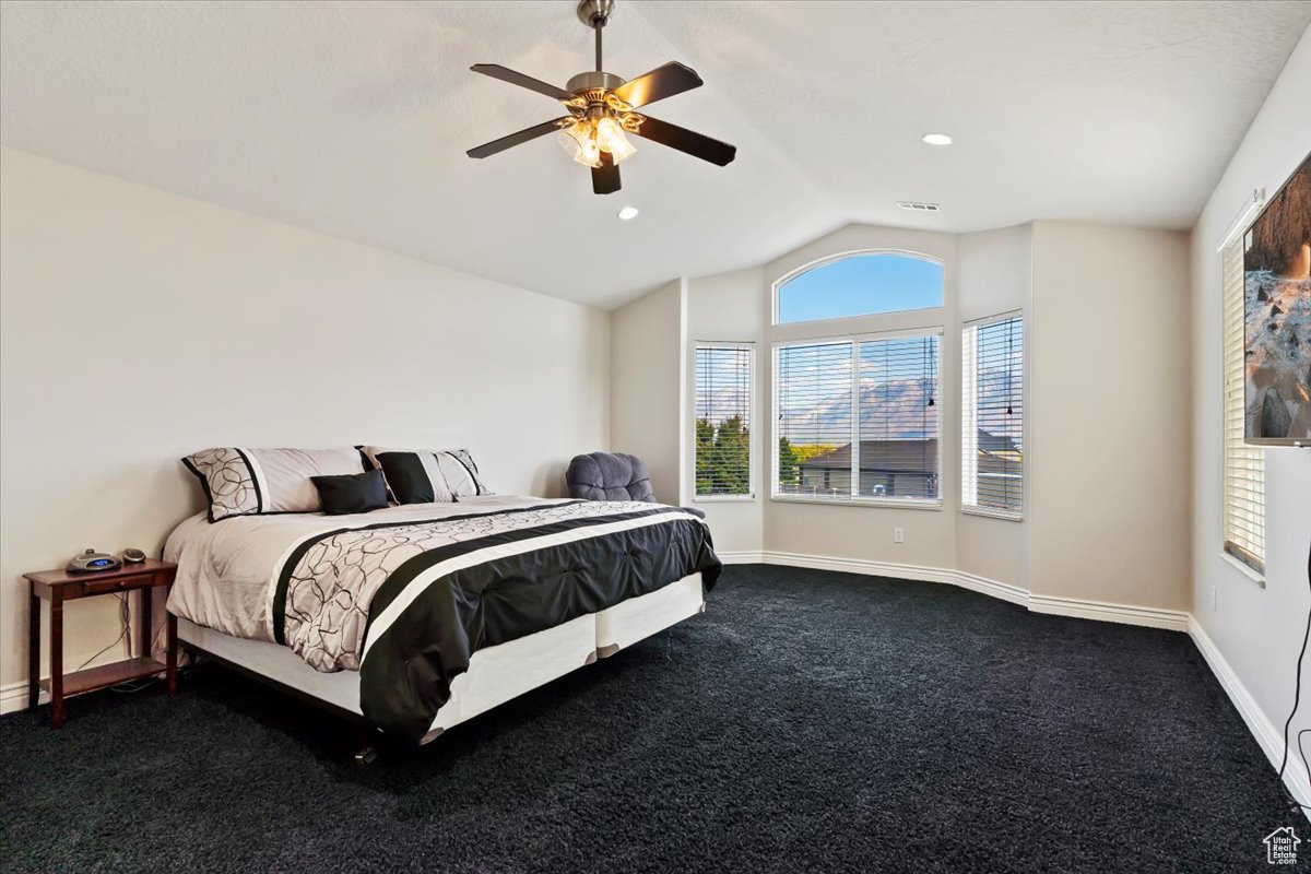 Carpeted bedroom featuring ceiling fan and lofted ceiling