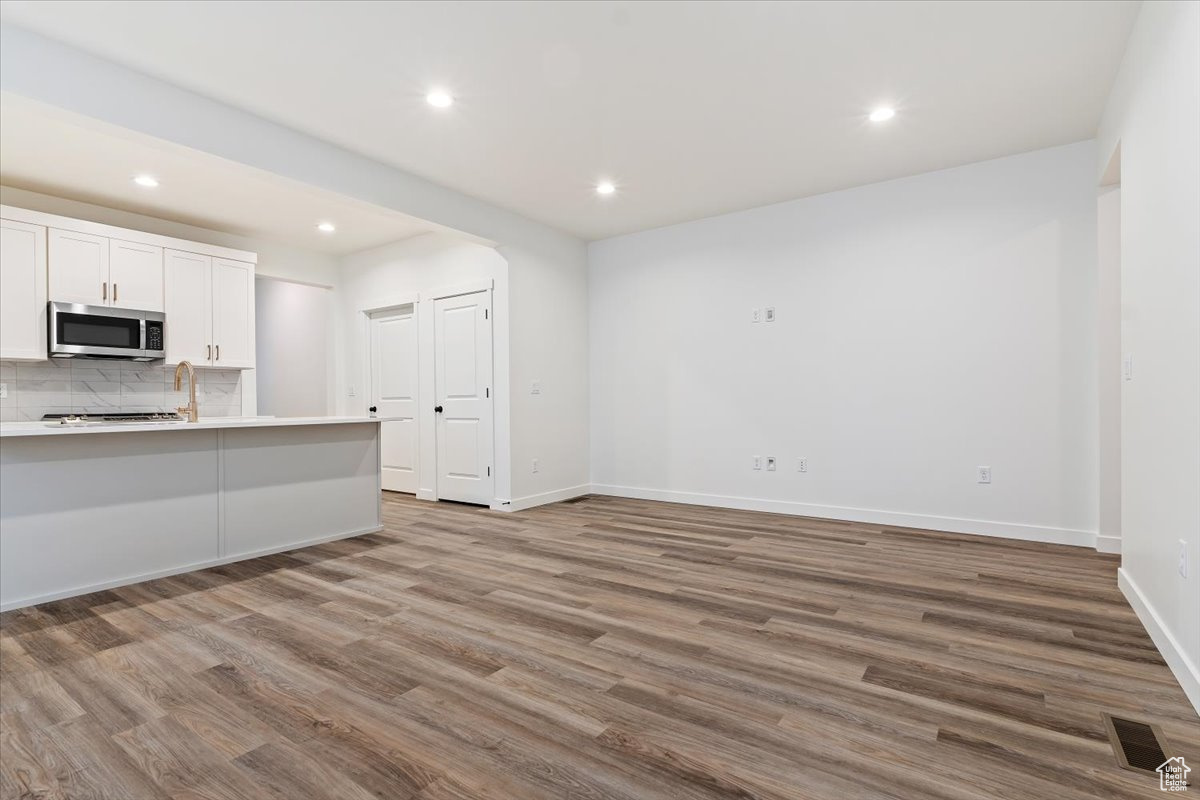 Kitchen featuring white cabinets, light hardwood / wood-style floors, and backsplash