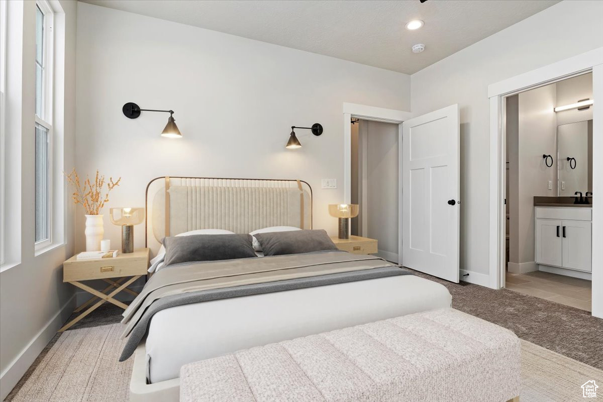 Bedroom with carpet floors, ensuite bathroom, and sink