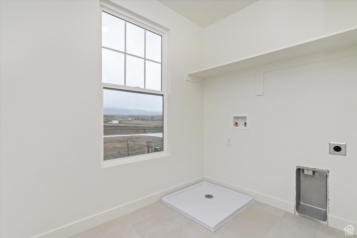 Clothes washing area featuring washer hookup, electric dryer hookup, and light tile patterned flooring