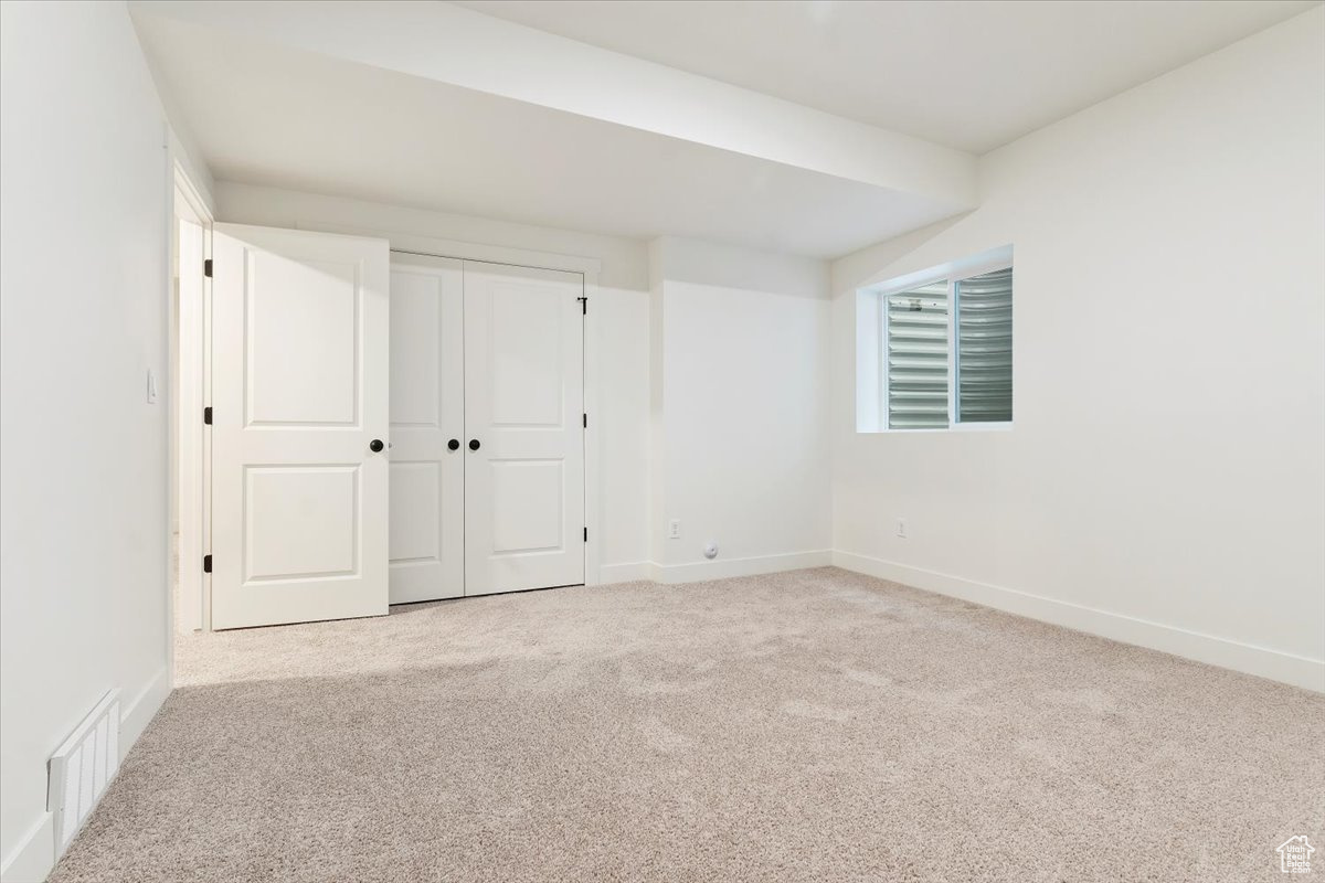 Unfurnished bedroom with light carpet and a closet