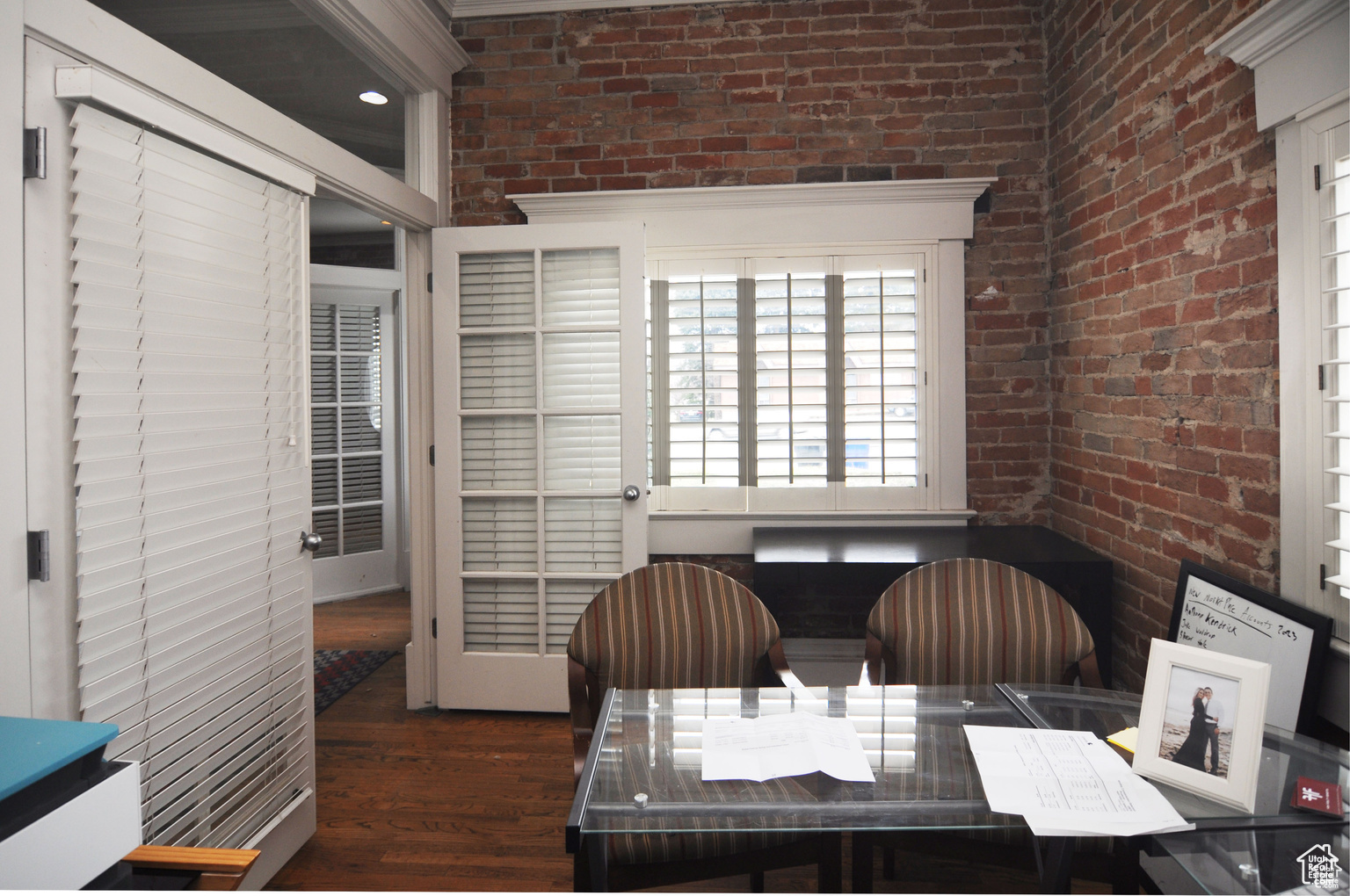 Office space featuring dark wood-type flooring and brick wall